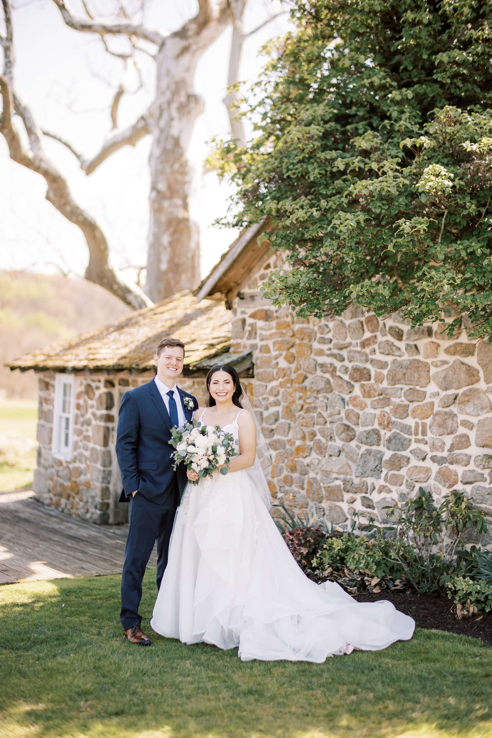 bride and groom pose by stone structure at French Creek Golf Club
