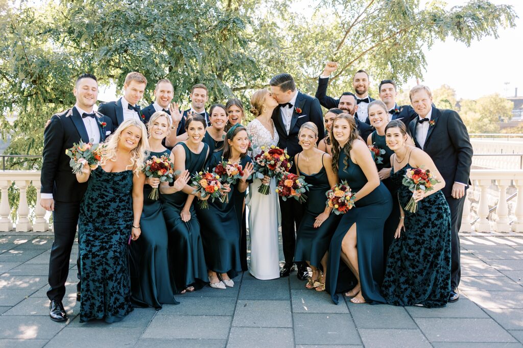 Philadelphia wedding venues - newlyweds kiss with bridesmaids in teal gowns and groomsmen in black suits around them