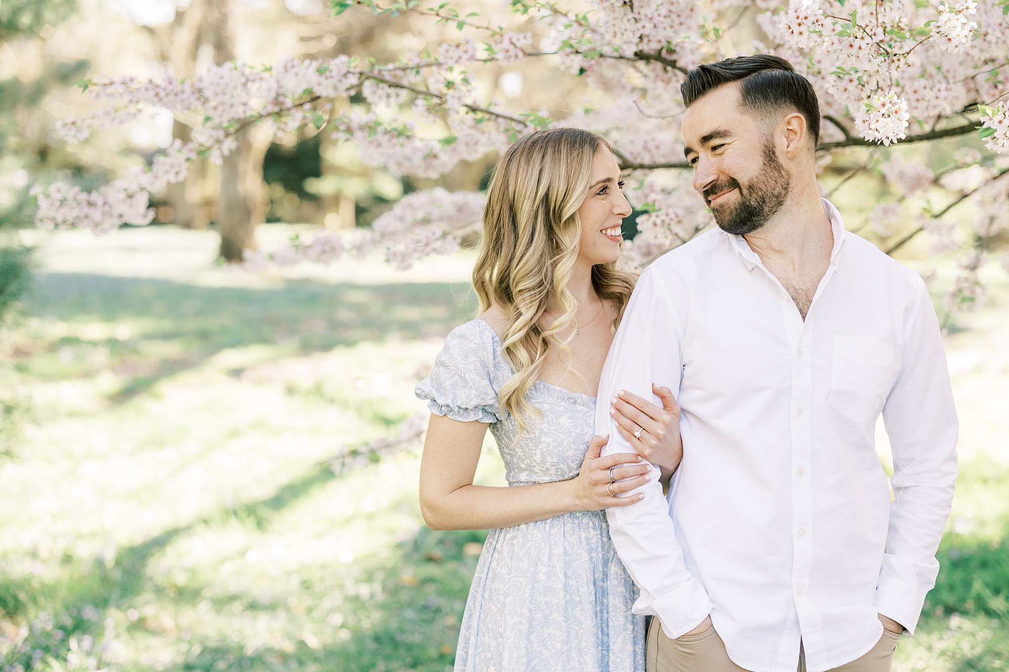 bride holds groom's arm in white button up shirt during Longwood Gardens engagement session