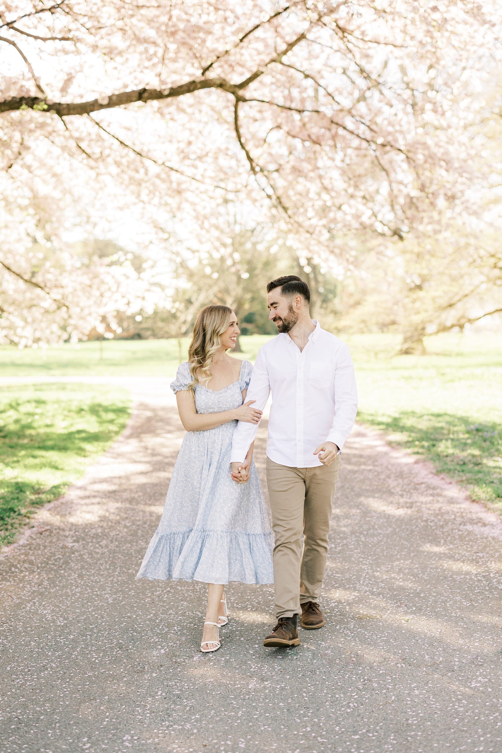 engaged couple walks down path at Longwood Gardens during spring engagement photos