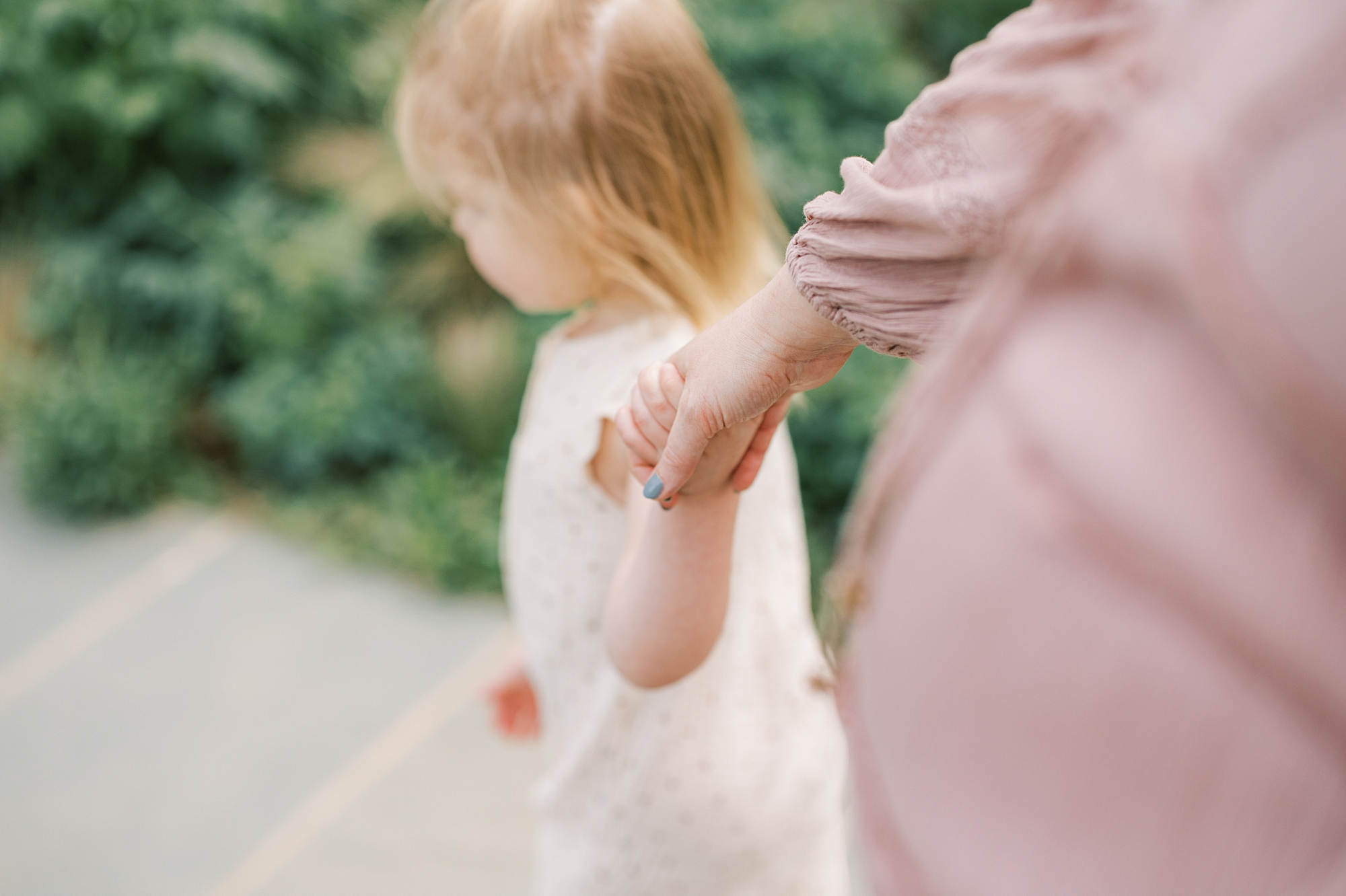 mom holds toddler's hand walking through Longwood Gardens