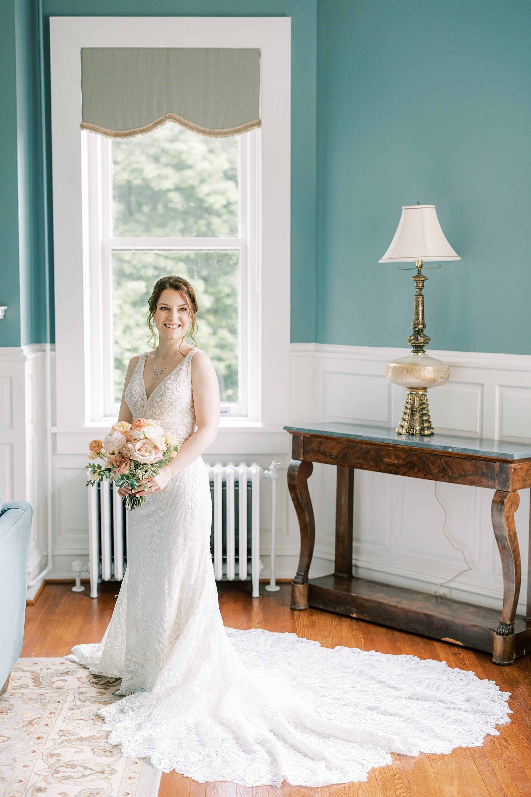 bride stands in front of window in room with teal walls at Bellevue Hall