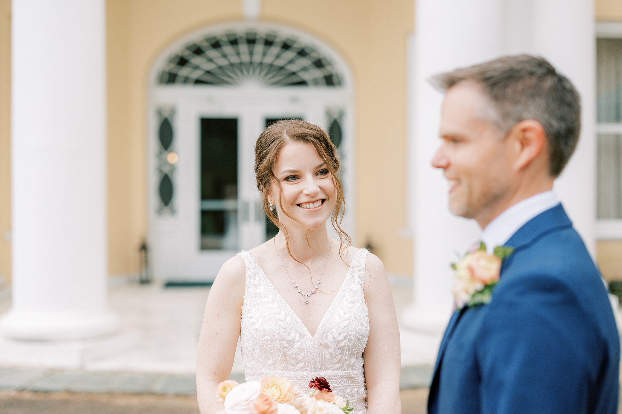bride smiles at groom during first look in courtyard at Bellevue Hall