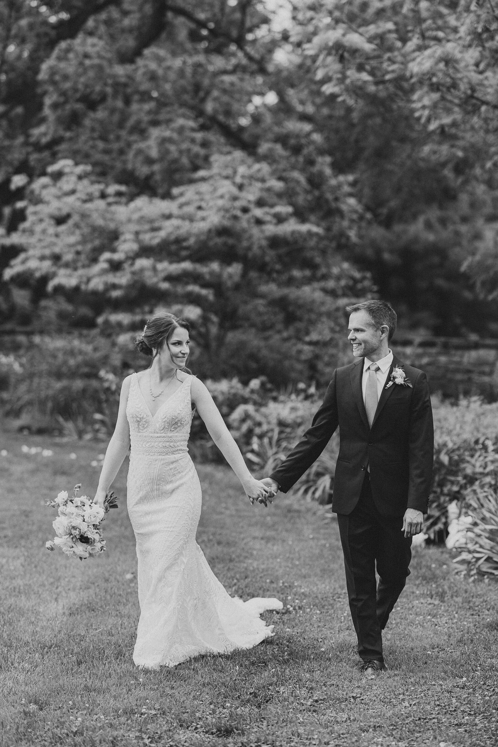 black and white portrait of bride and groom holding hands on summer wedding day