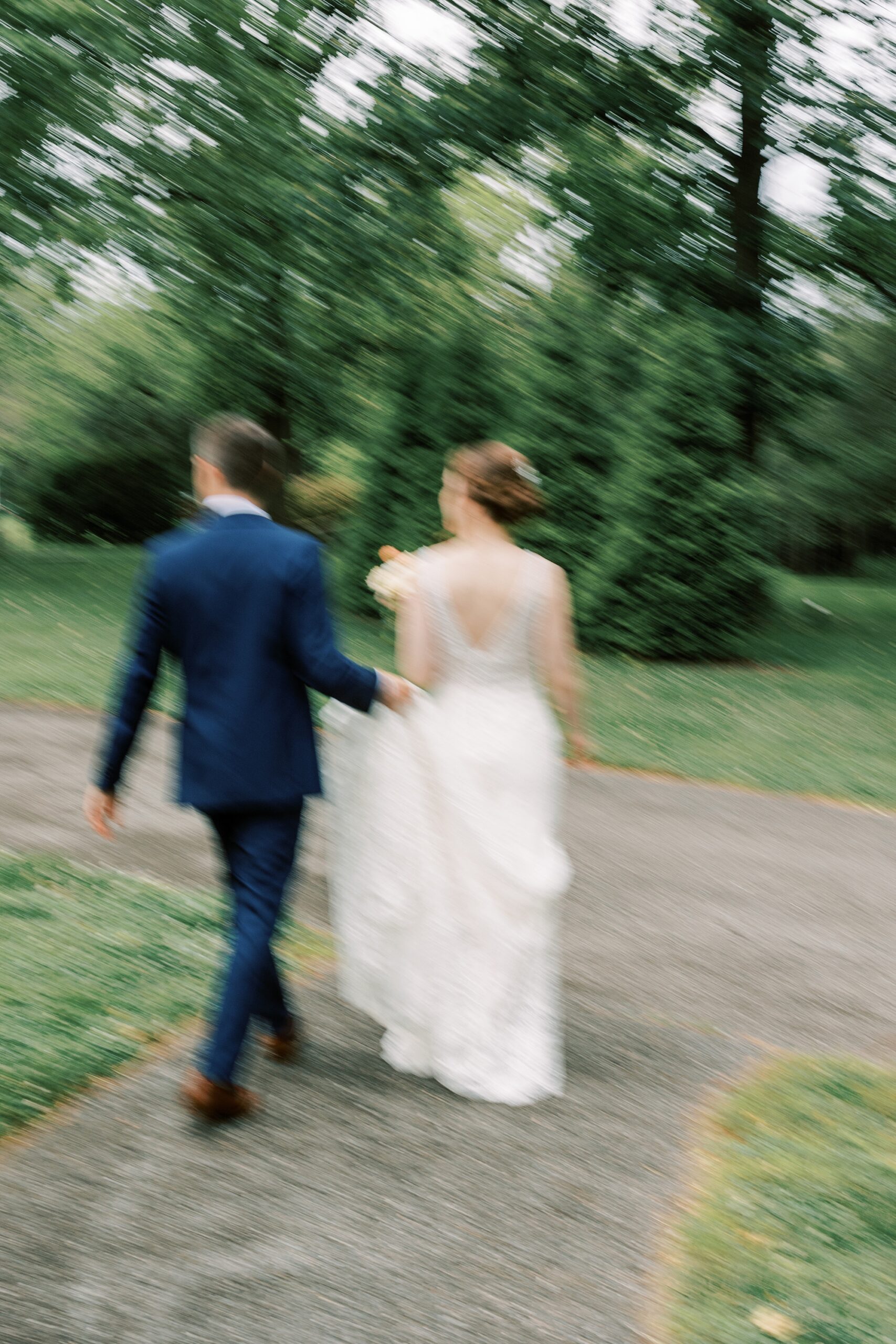 blurred portrait of bride and groom walking down path at Bellevue Hall