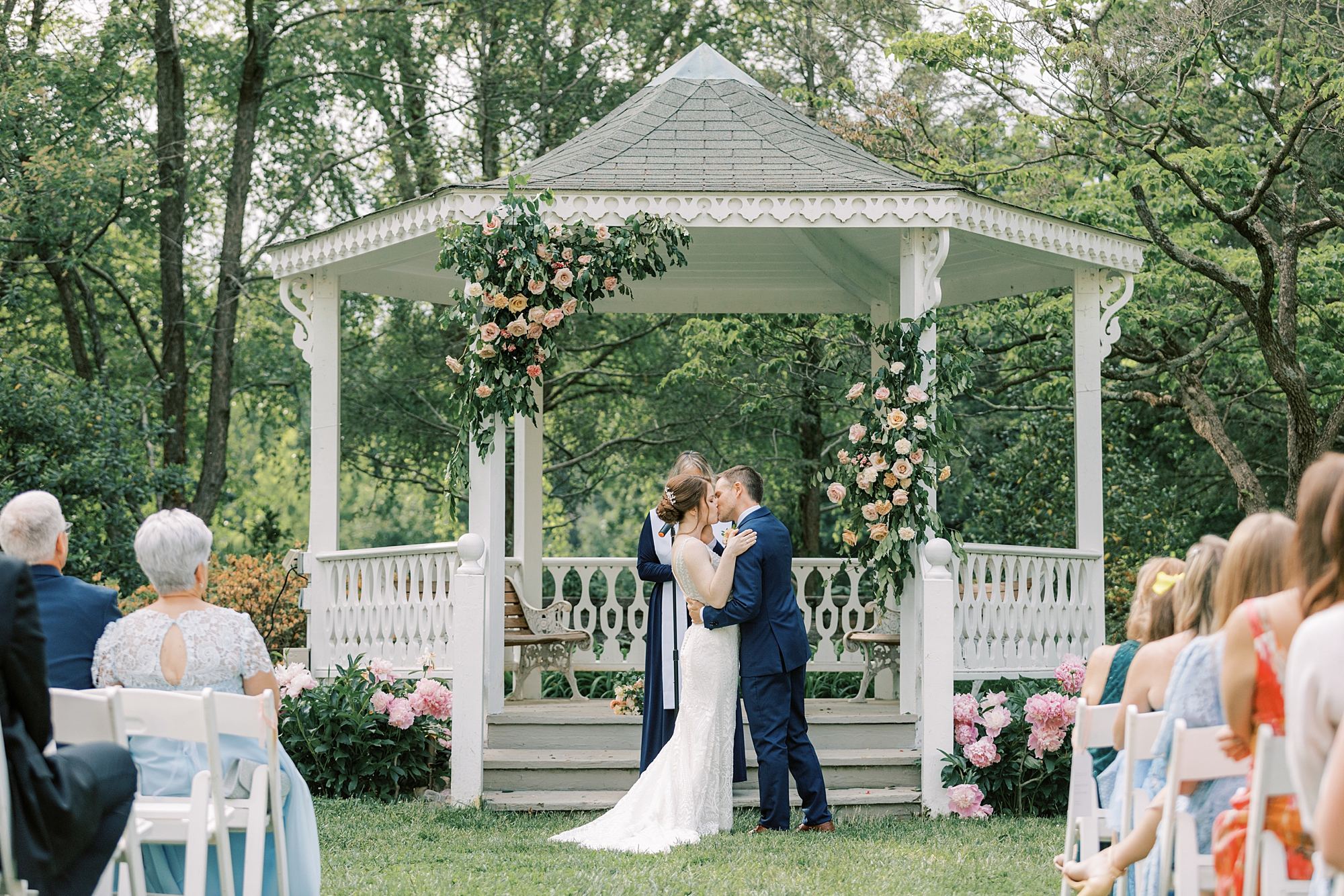 bride and groom kiss during wedding ceremony on lawn at Bellevue Hall
