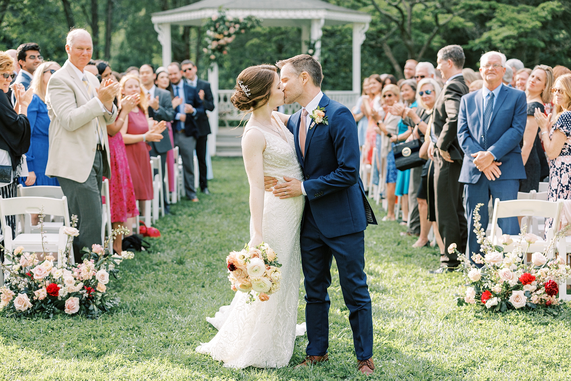 newlyweds kiss in aisle after wedding ceremony on lawn at Bellevue Hall