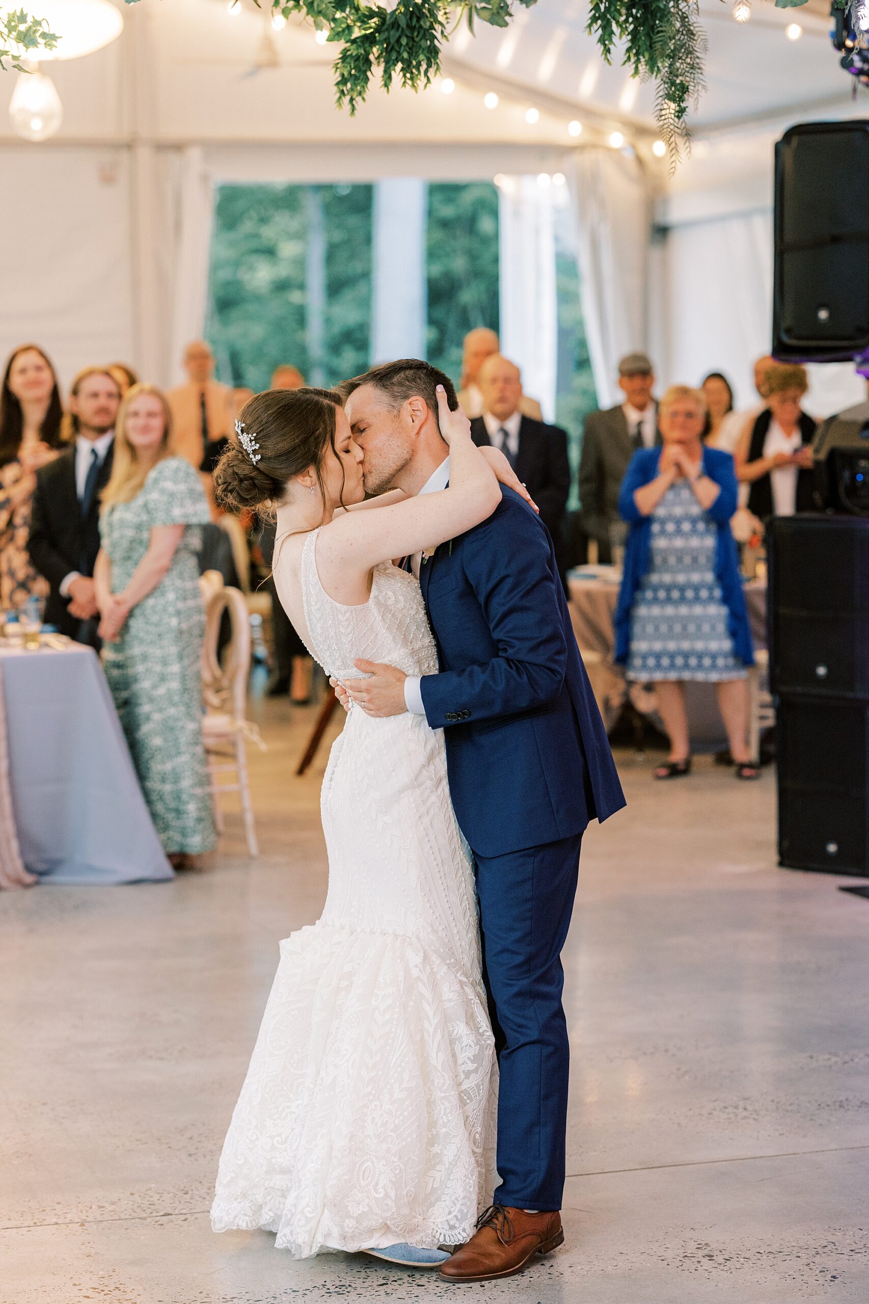 bride and groom kiss on dance floor after first dance 