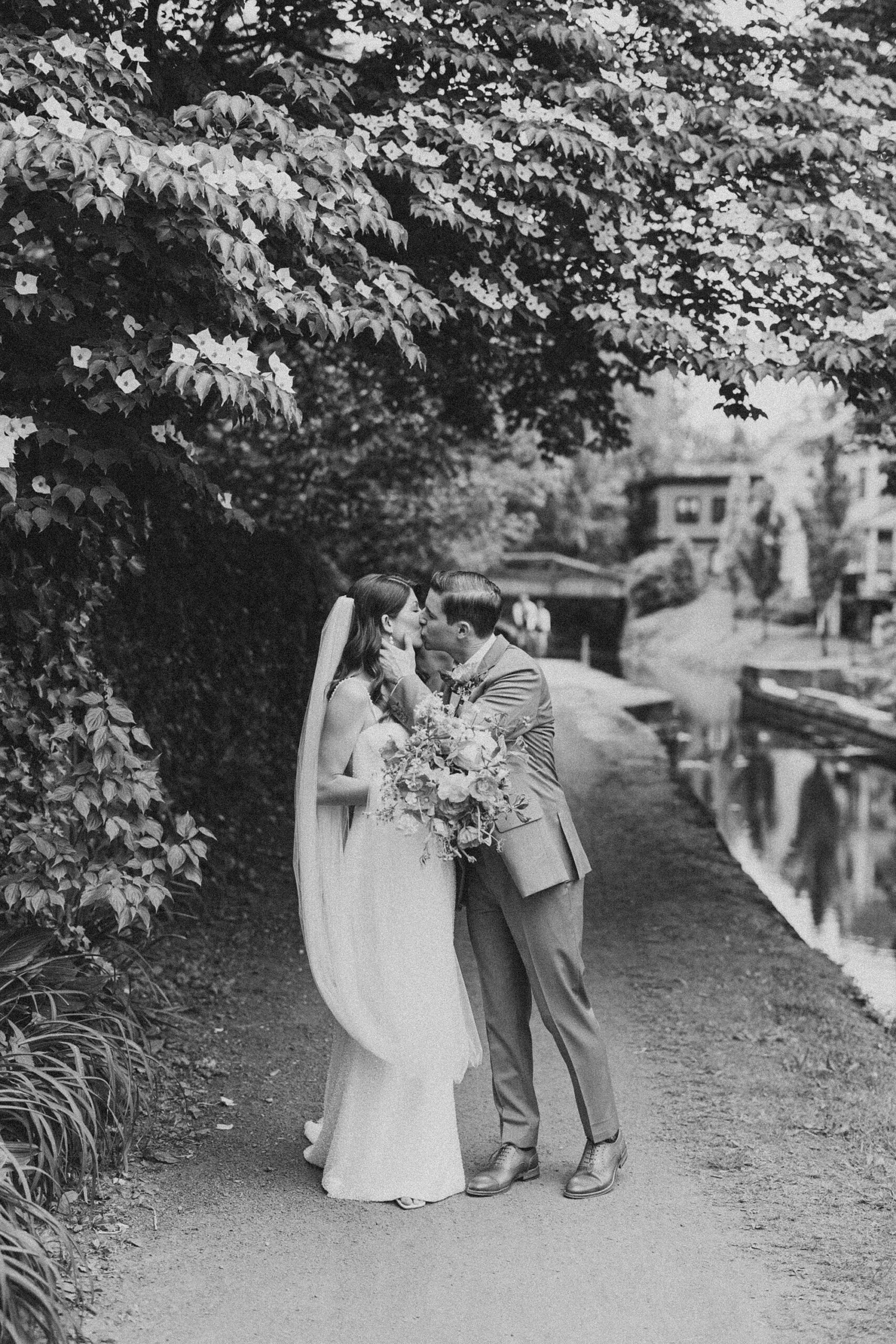 groom leans to kiss bride on path in New Hope PA