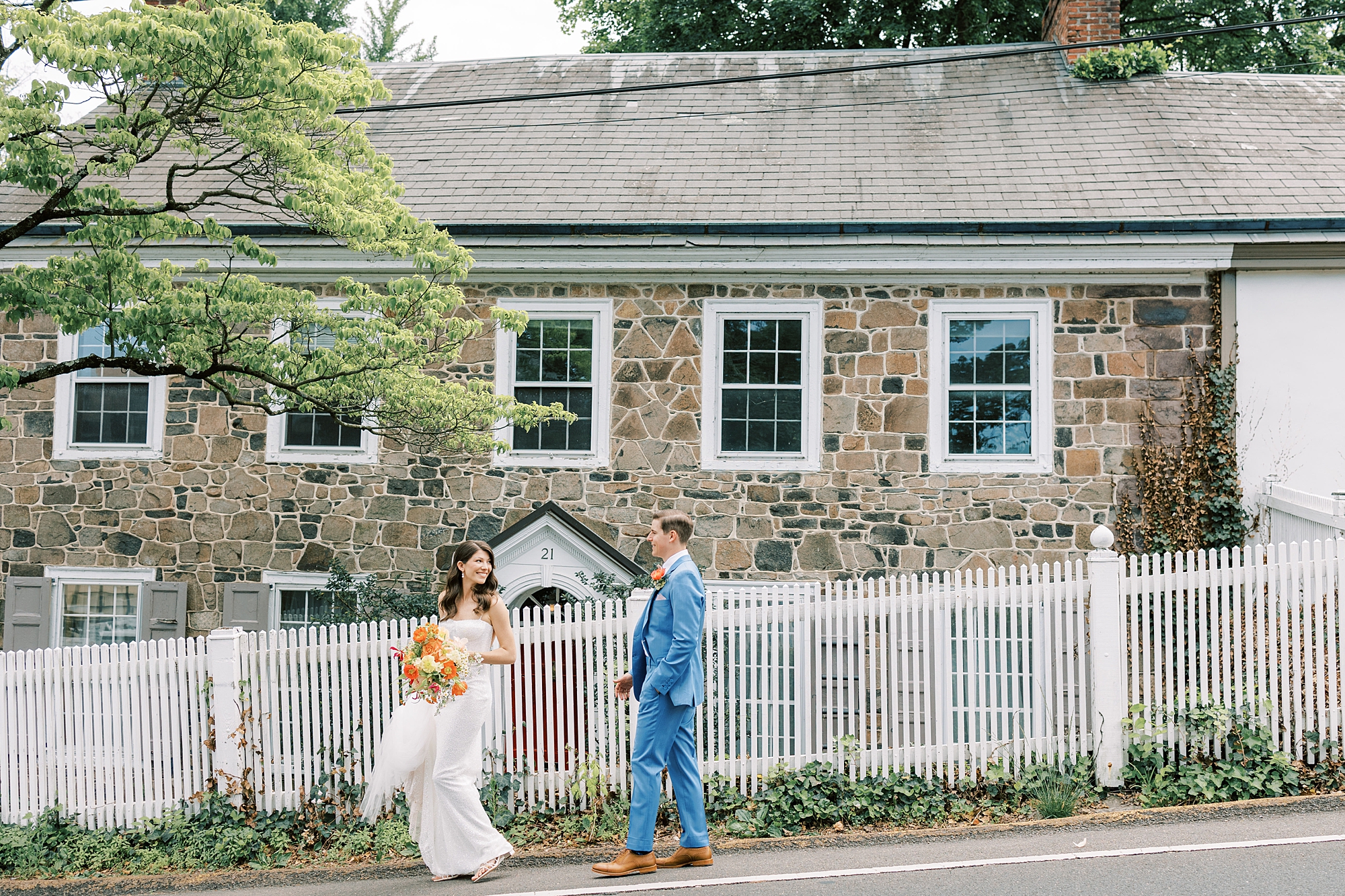 bride and groom walk next to white fence in New Hope PA