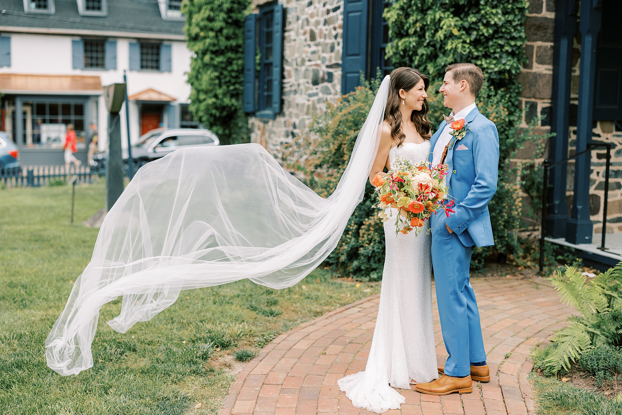 groom in blue suit smiles at bride with veil behind her in New Hope PA
