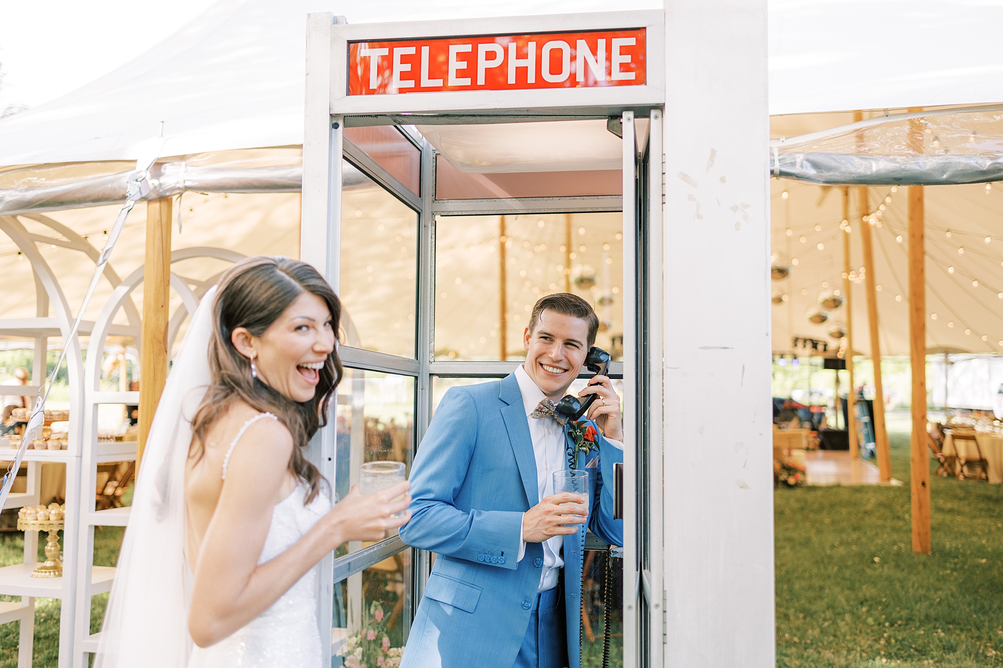 bride and groom laugh using telephone booth during reception at Bowman's Hill Wildflower Preserve