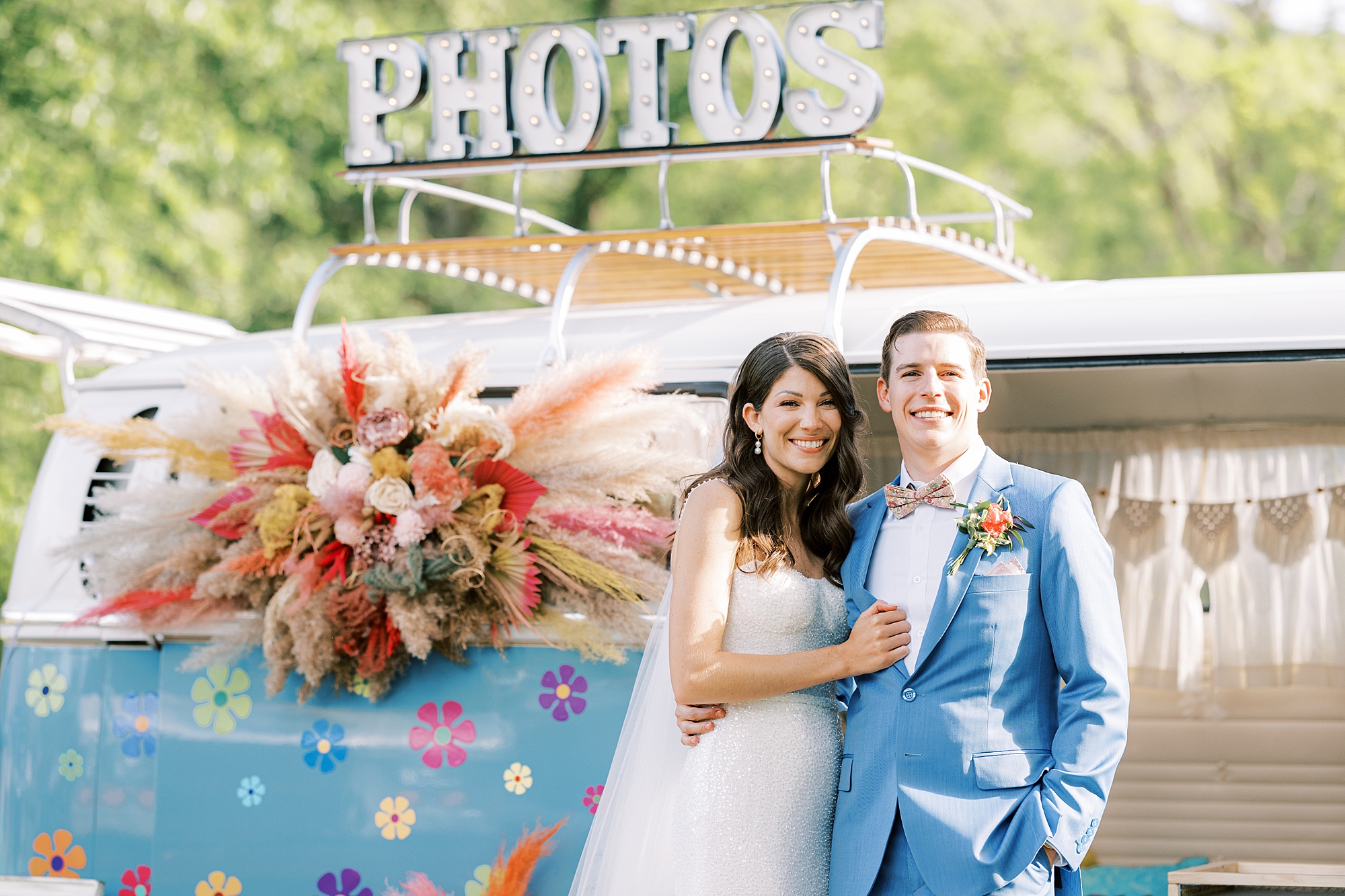 bride and groom smile leaning against VW bus photo booth 