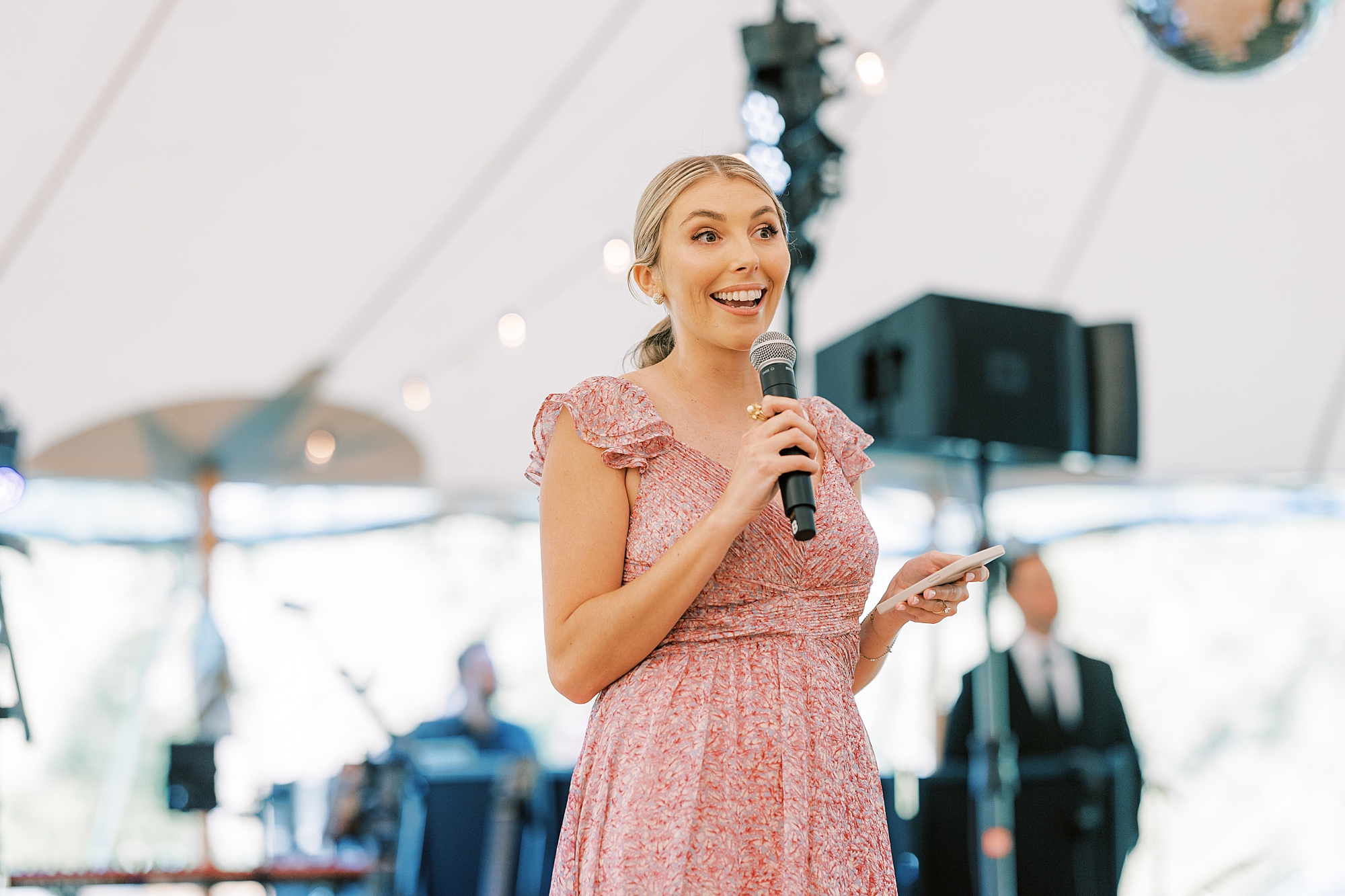 bridesmaid grins during speech in tented wedding reception at Bowman's Hill Wildflower Preserve