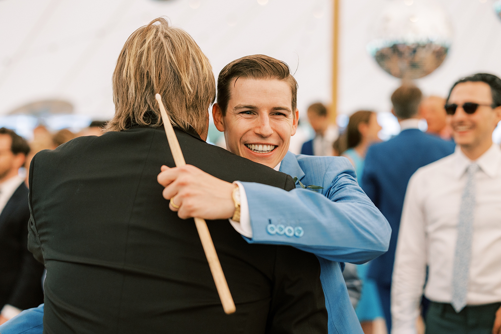 groom hugs drummer during wedding reception 