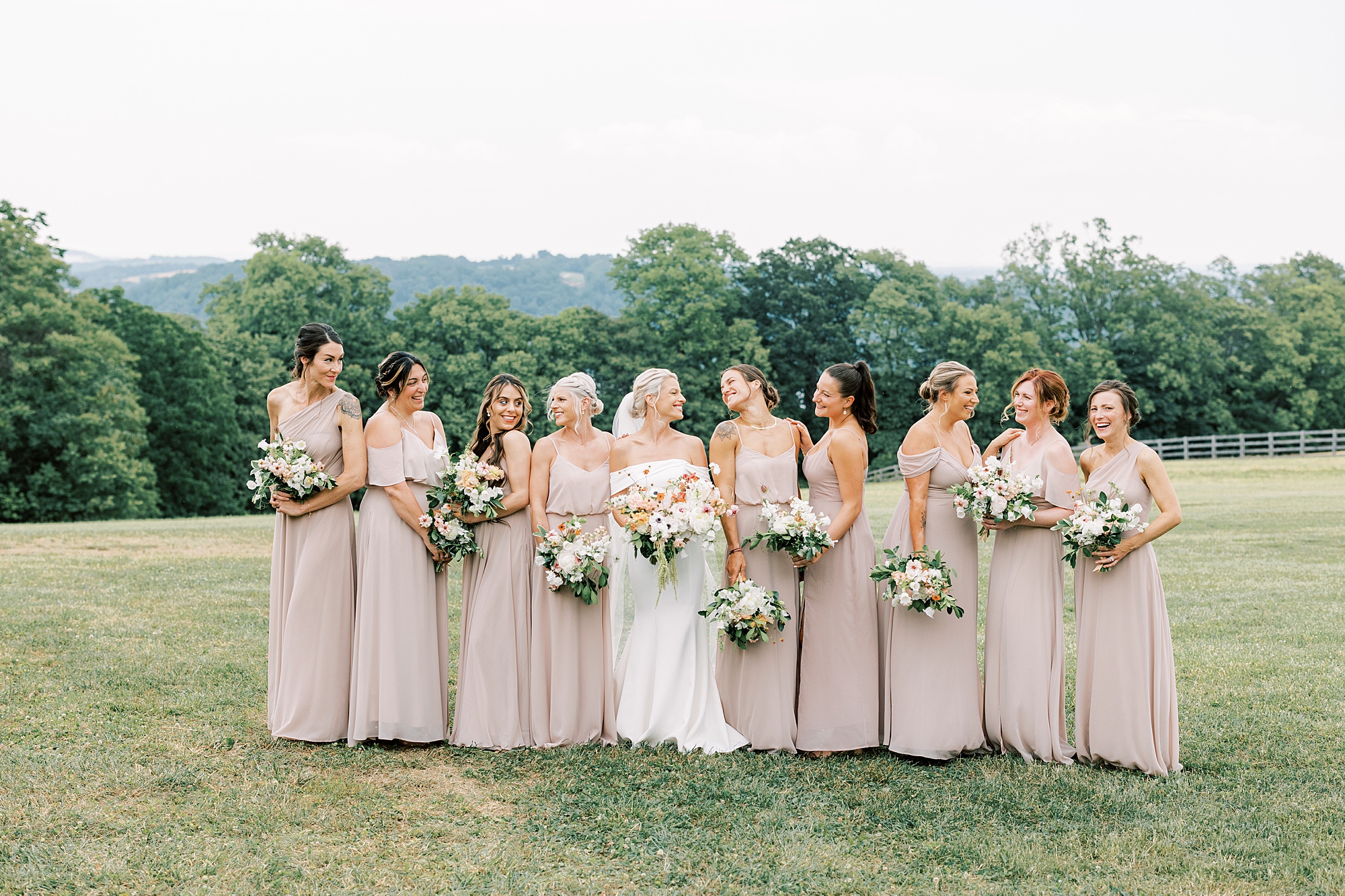 bride smiles at bridesmaids in pink gowns on lawn at Lauxmont Farms