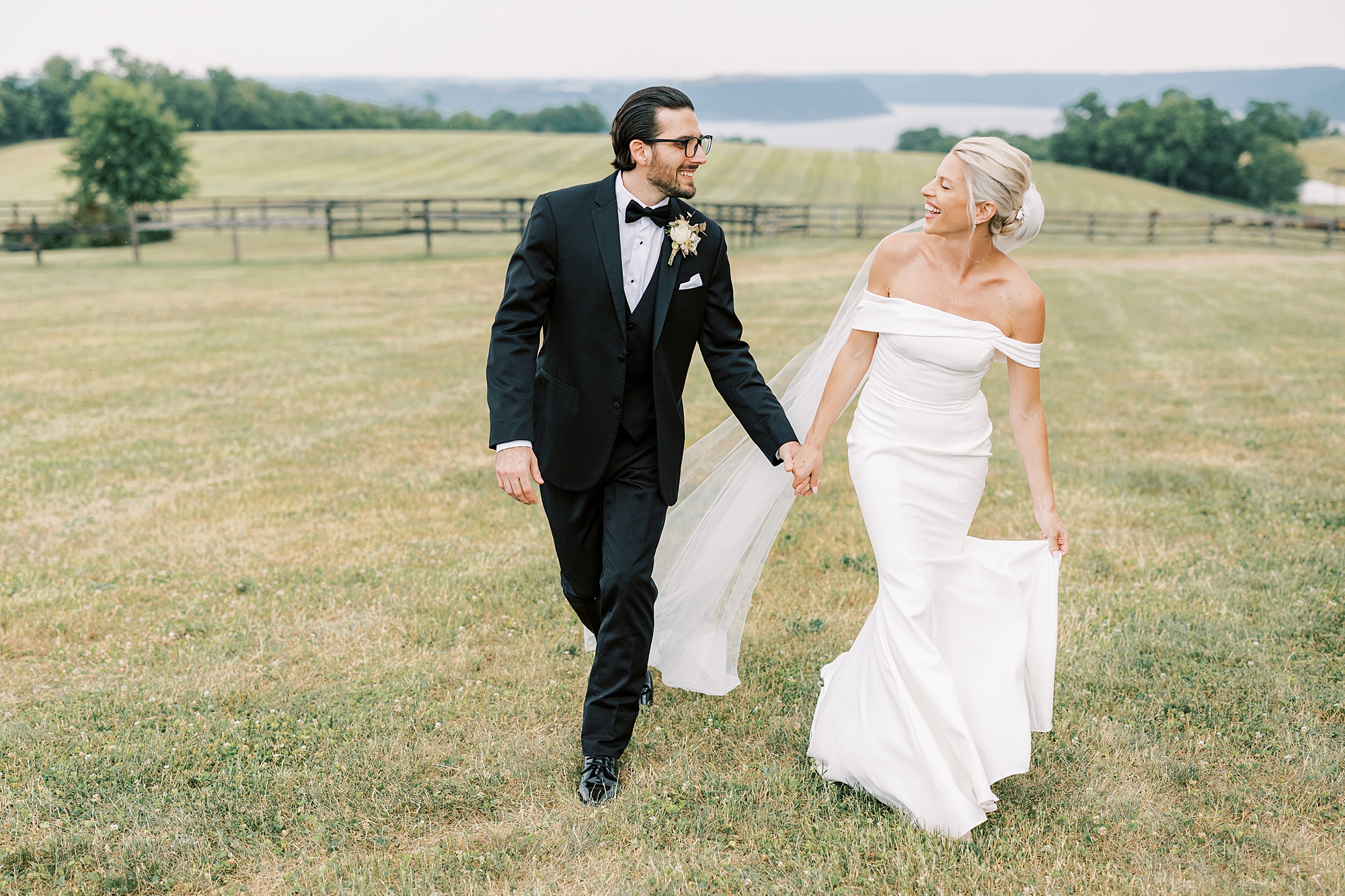 bride and groom hold hands walking on lawn in front of mountains at Lauxmont Farms