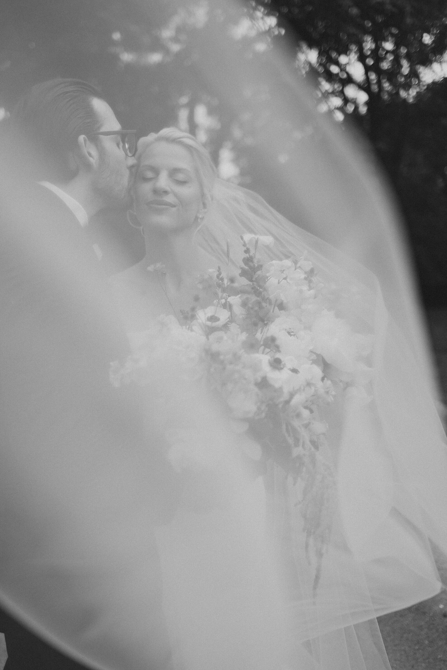 bride and groom kiss in photo taken through bride's veil