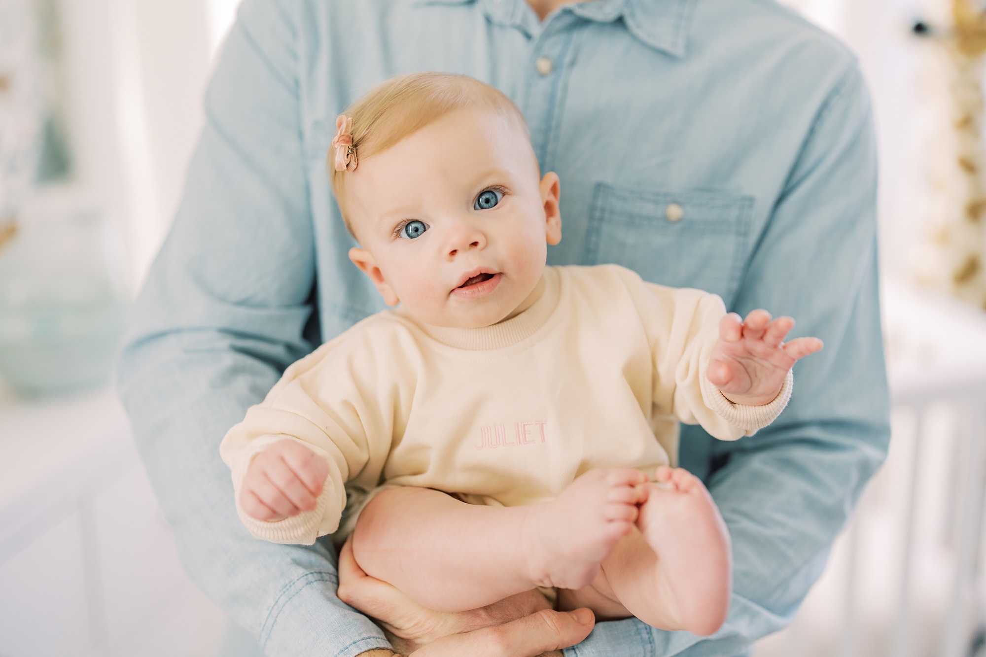 man in light blue shirt holds toddler in arms during lifestyle milestone portraits