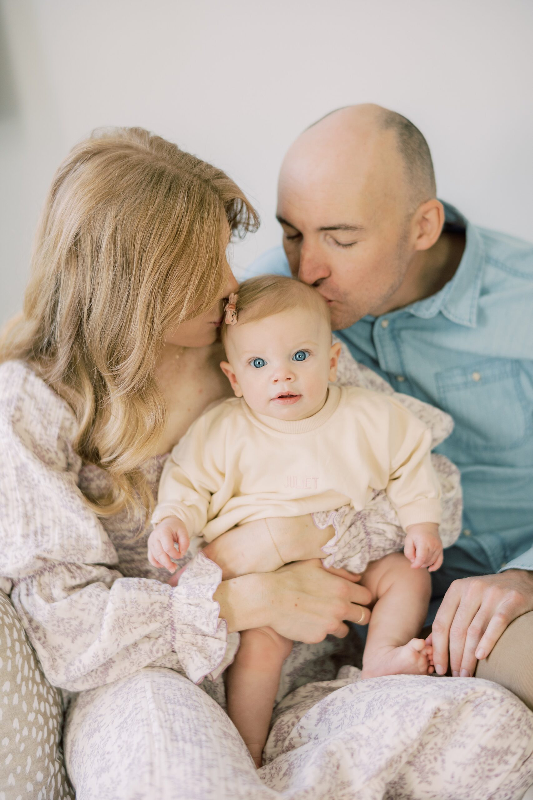 parents lean to kiss baby's head during lifestyle milestone portraits in Glen Mills PA