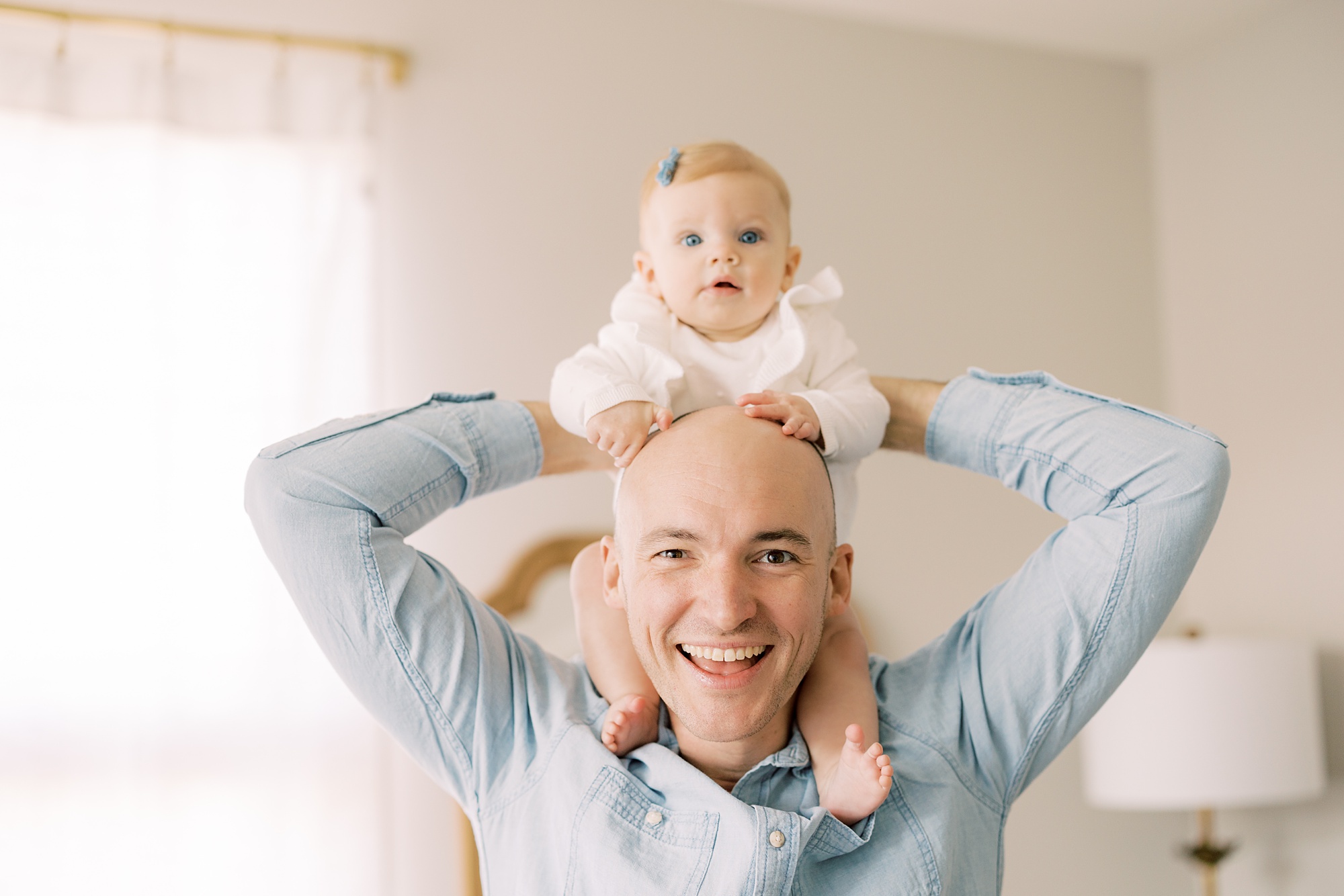 dad holds 6 month old toddler on shoulders during lifestyle milestone portraits