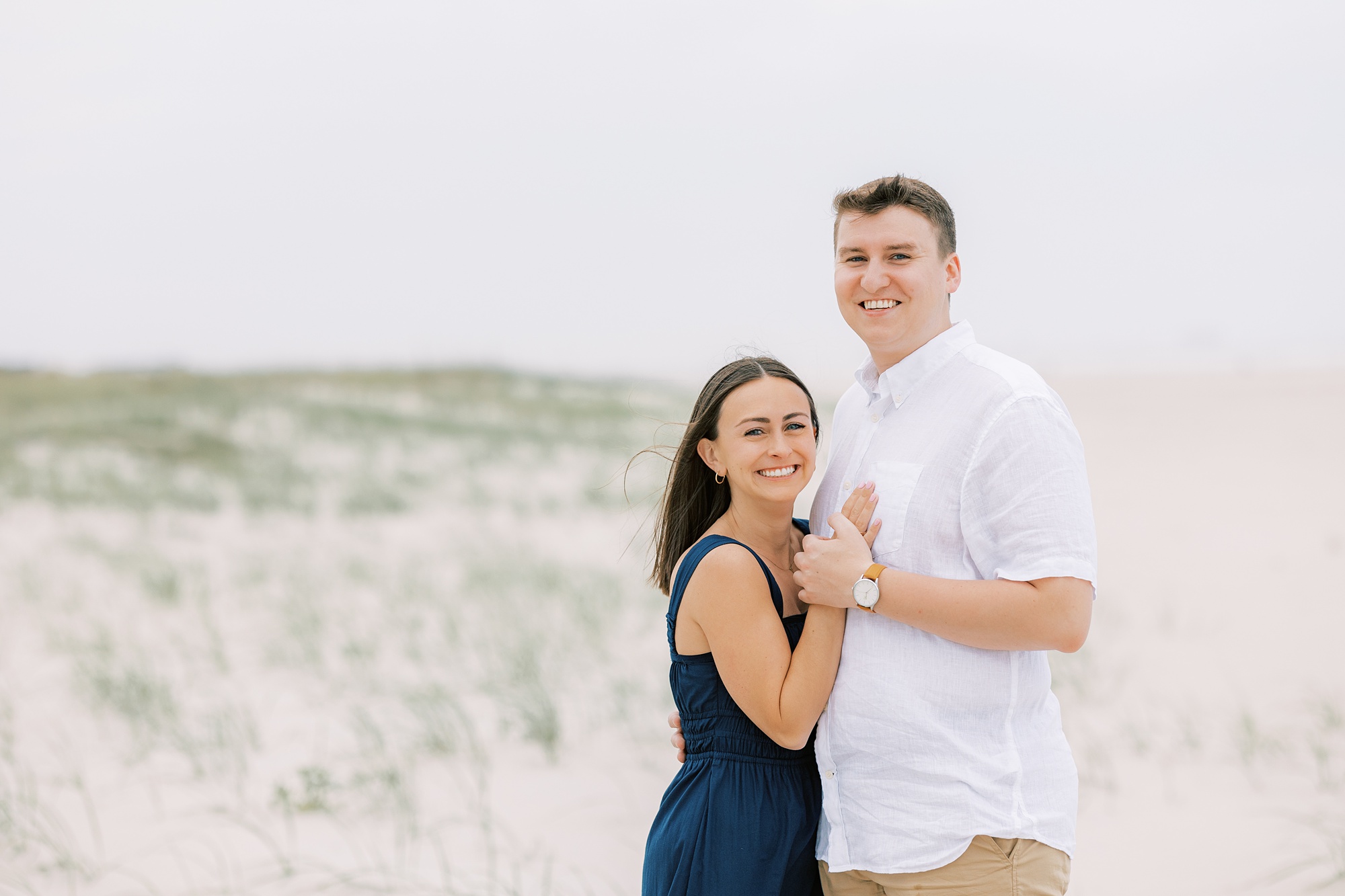 bride and groom hold hands hugging on beach during Ocean City NJ engagement photos