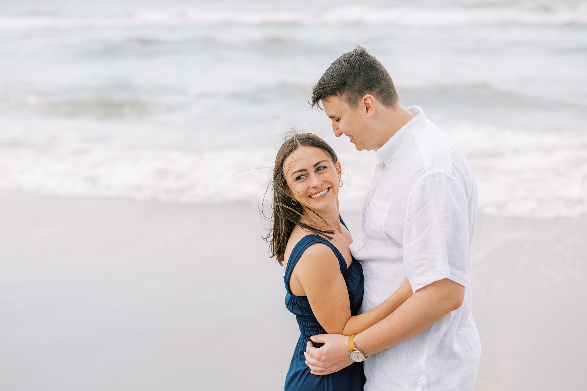 man in white shirt looks down at woman in teal dress during Ocean City NJ engagement photos