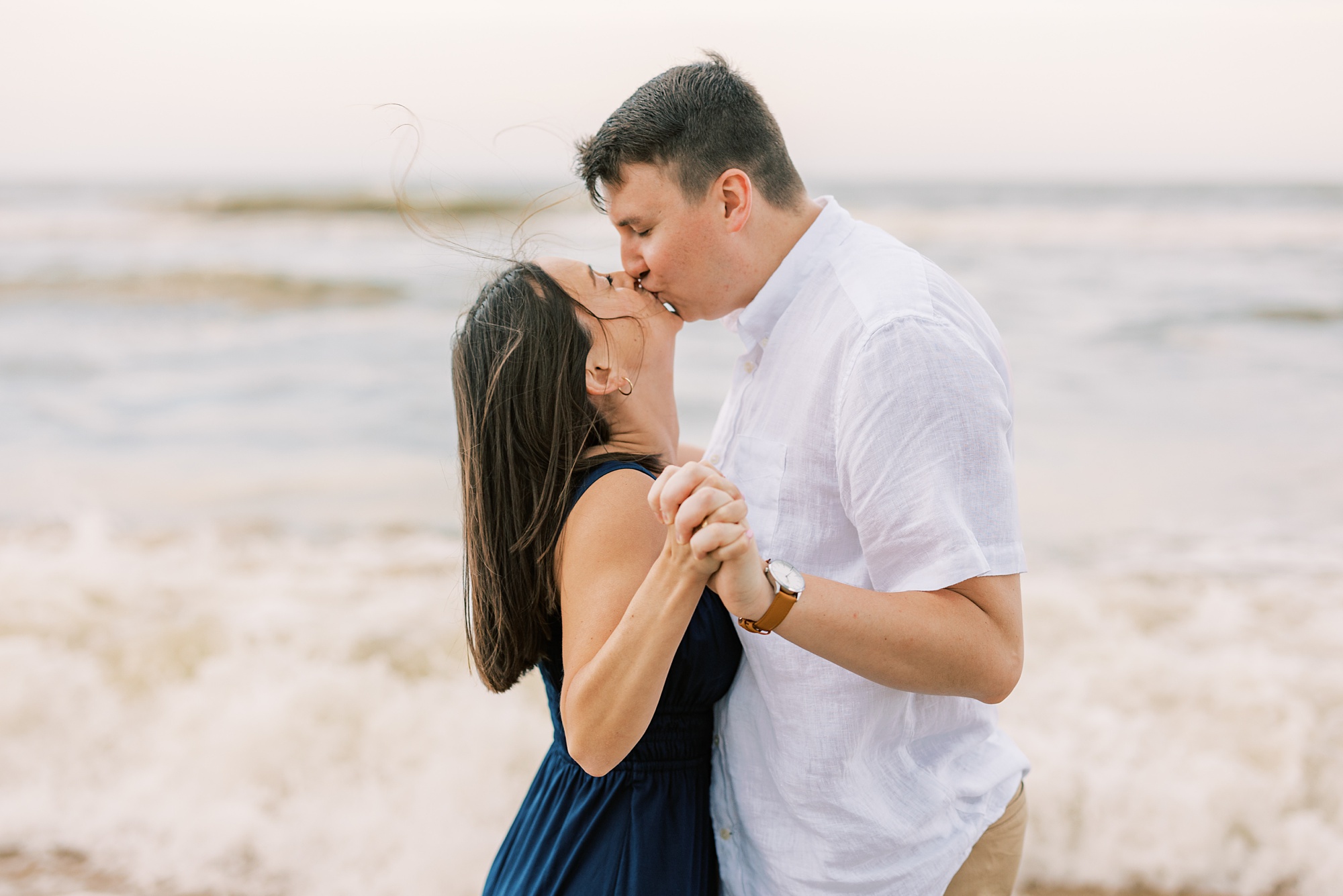 couple holds hands leaning to kiss during Ocean City NJ engagement photos