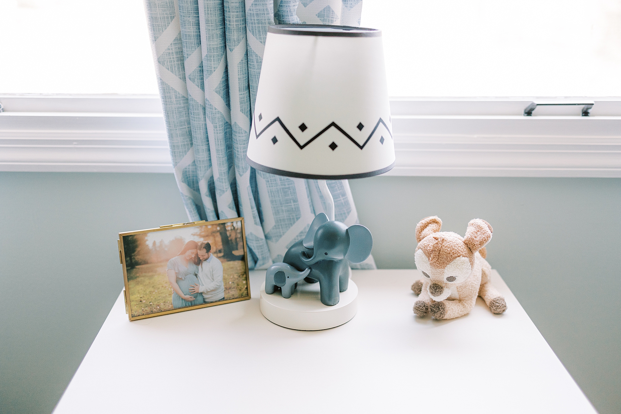 stuffed animal deer sits by blue and white lamp in nursery 