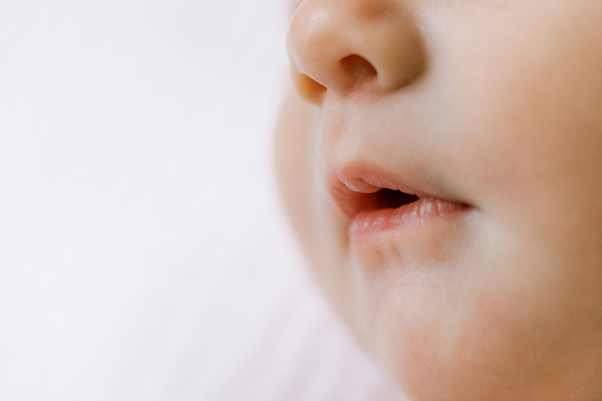 closeup of baby's mouth on white sheets 