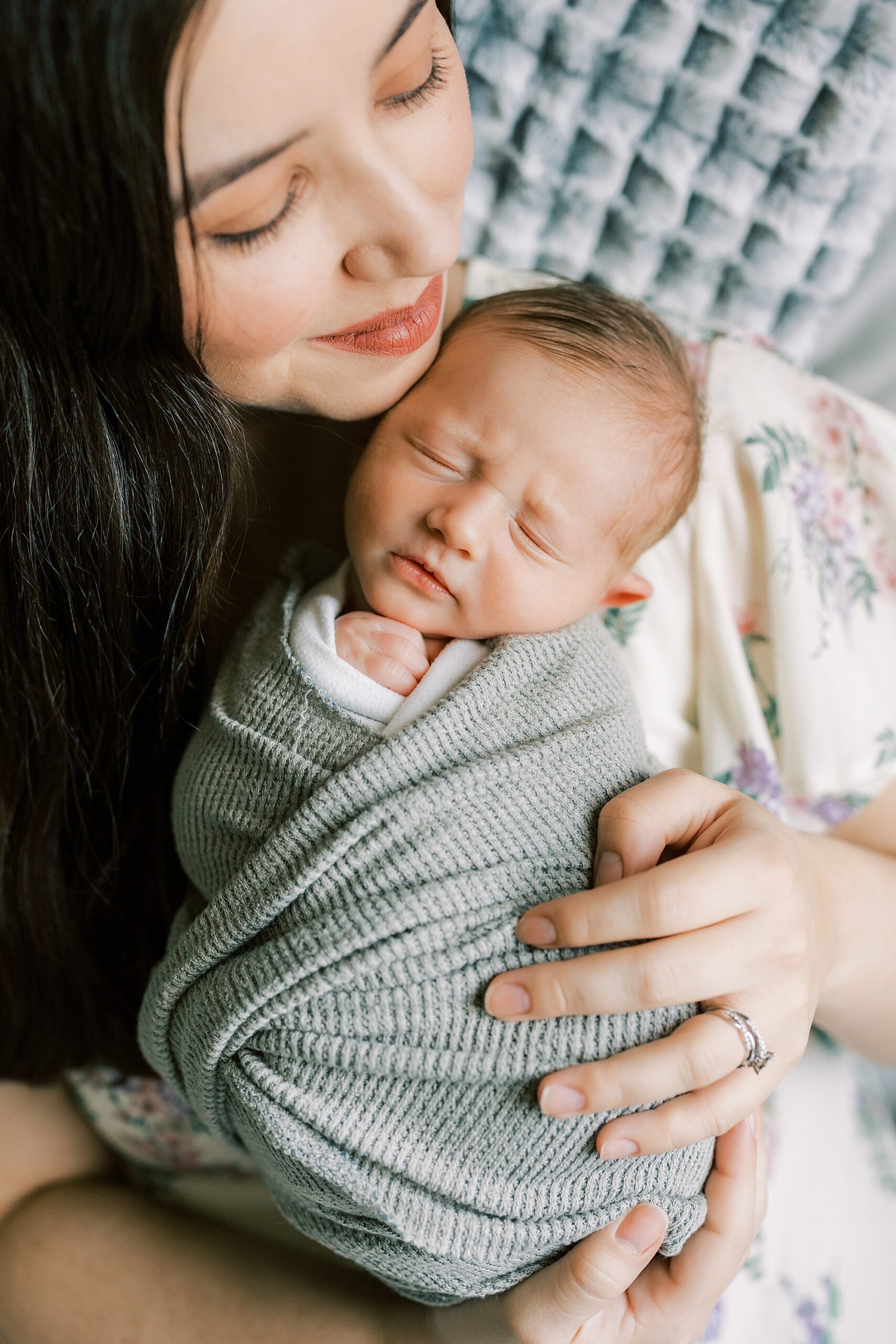 mom snuggles with son in green wrap on chest during Philadelphia newborn portraits