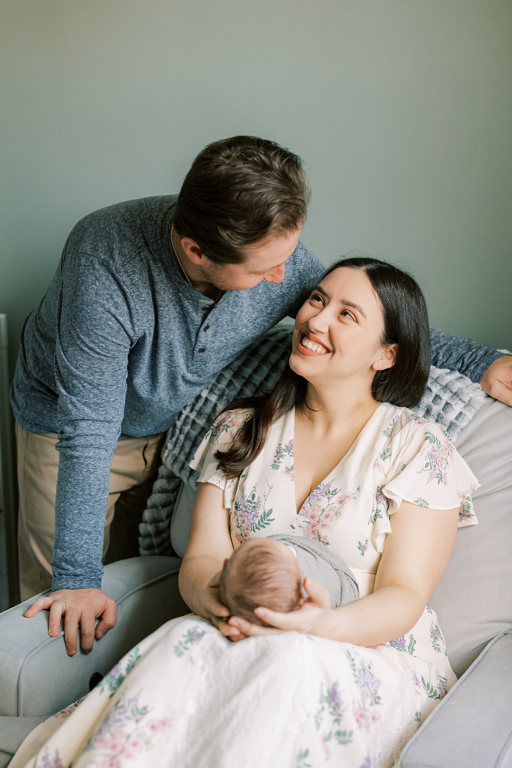 new parents smile at each other while mother holds son