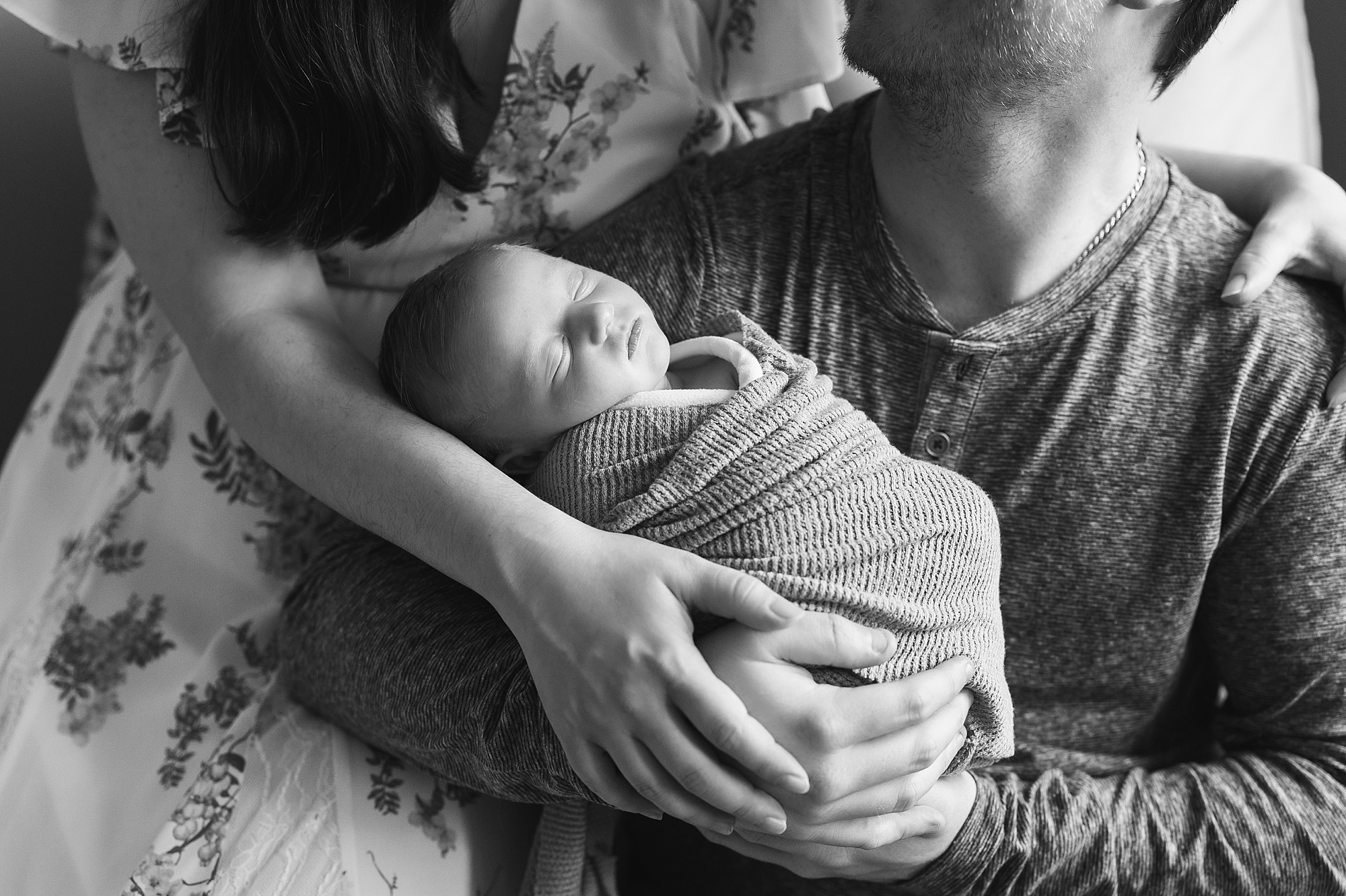 black and white portrait of couple holding new baby boy at home