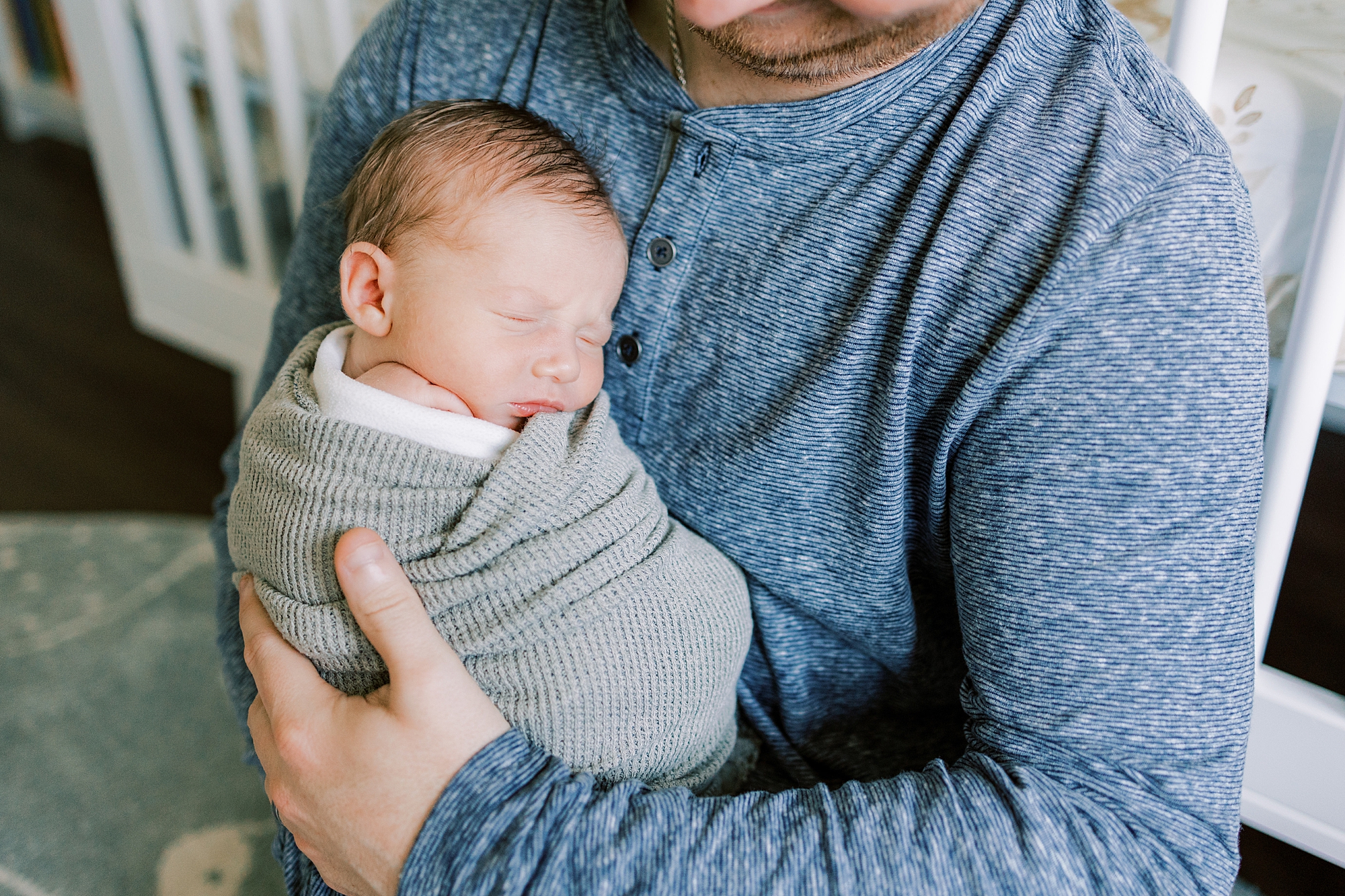 baby boy curls up on dad's chest during Philadelphia newborn portraits