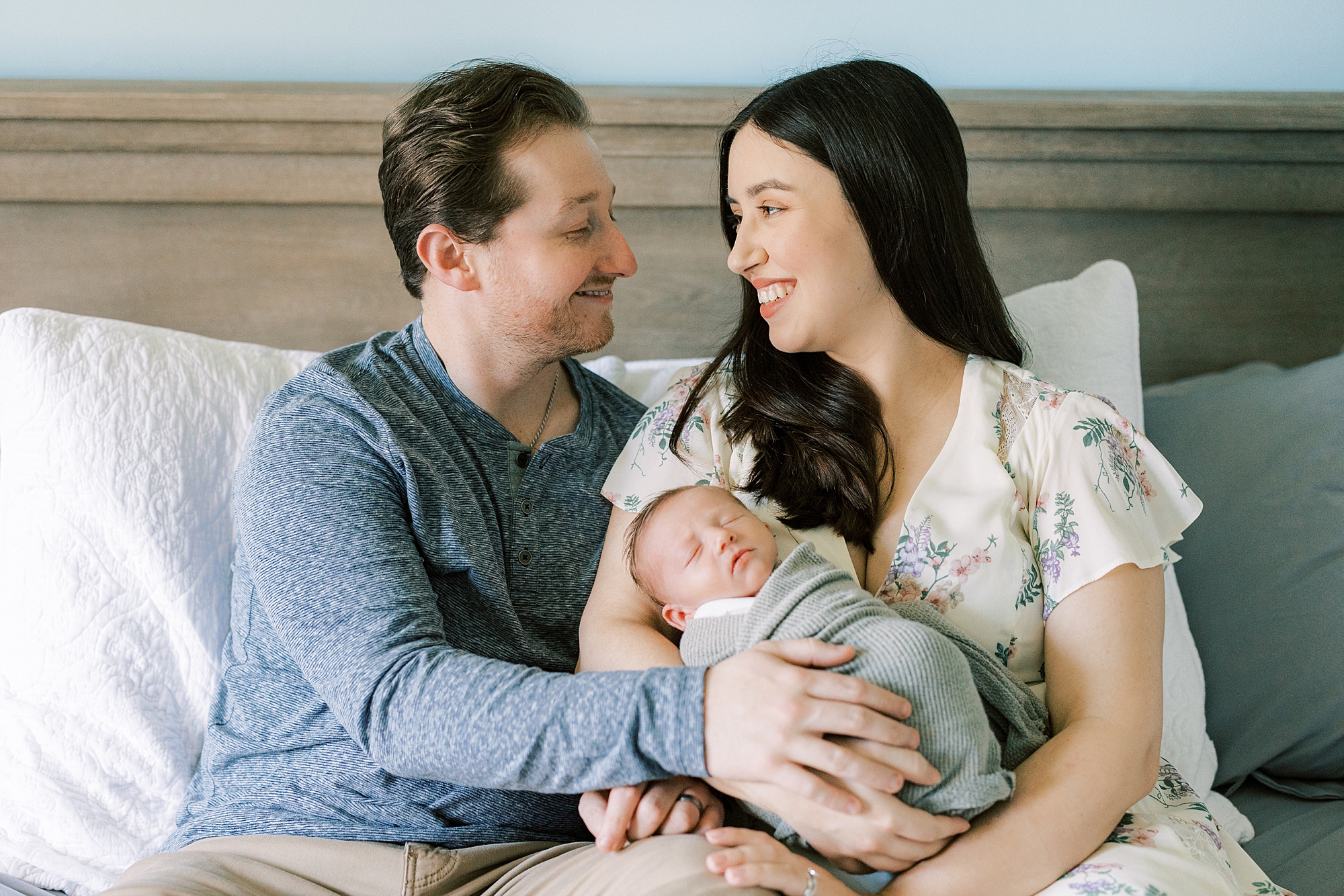 mom and dad sit on bed holding son during Philadelphia newborn portraits