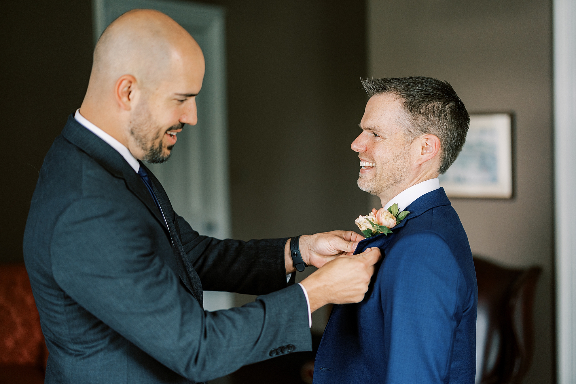 man helps groom with tie and boutonnière during prep for DE wedding
