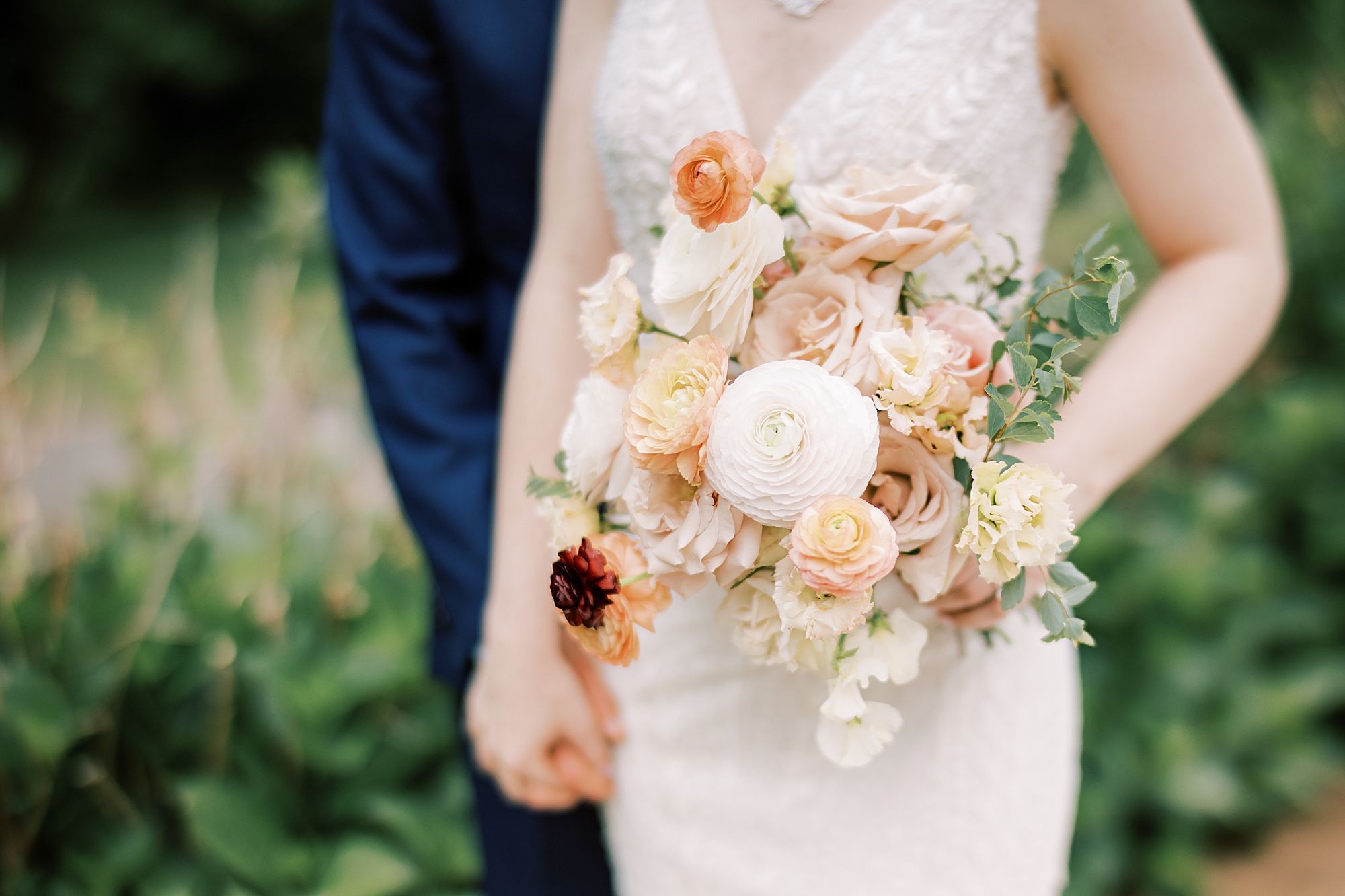 bride holds bouquet of white and dusty pink flowers for summer wedding 