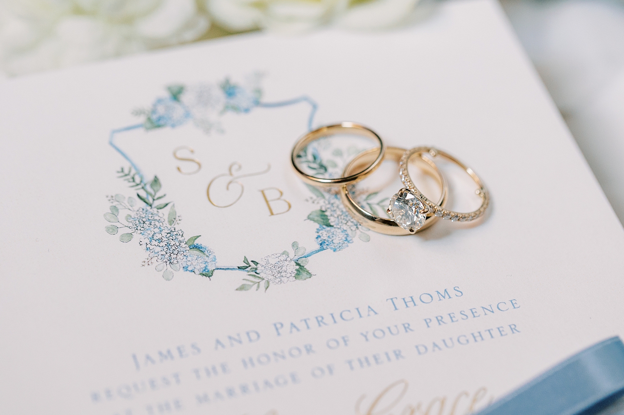 gold wedding bands lay on invitation suite with custom crest 