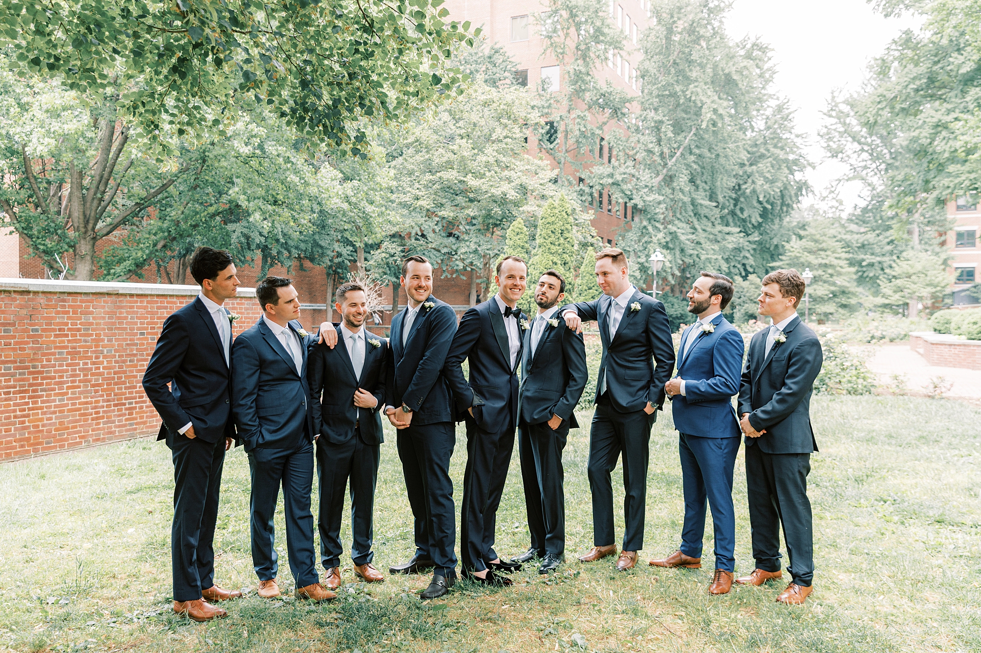 groom stands with groomsmen in navy suits in Philadelphia garden 