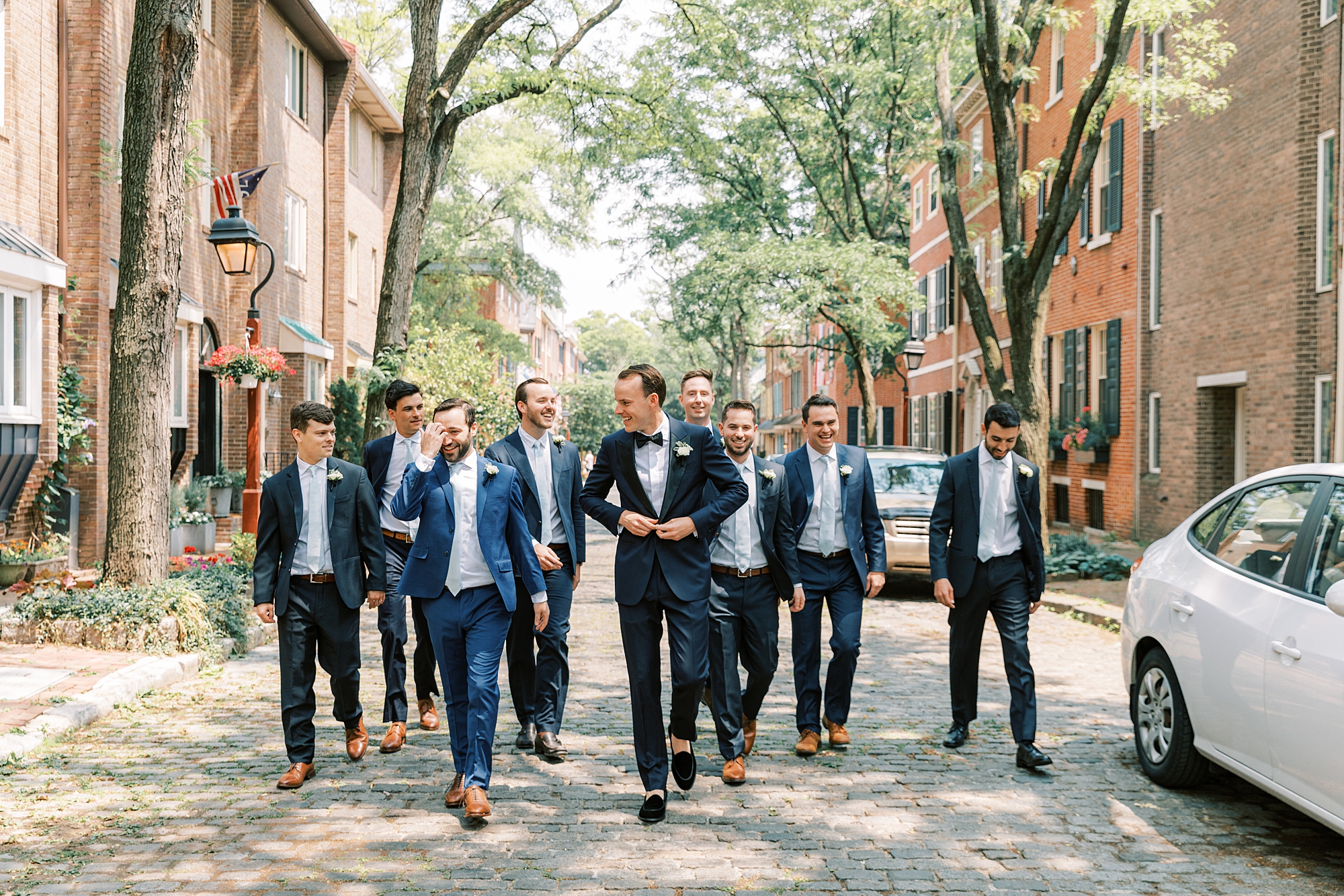 groom walks down cobblestone street with groomsmen in Philly 