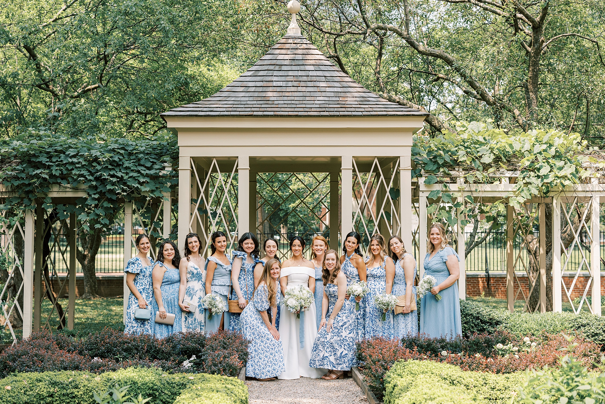 bride and bridesmaids pose by gazebo in Philadelphia Signers Garden