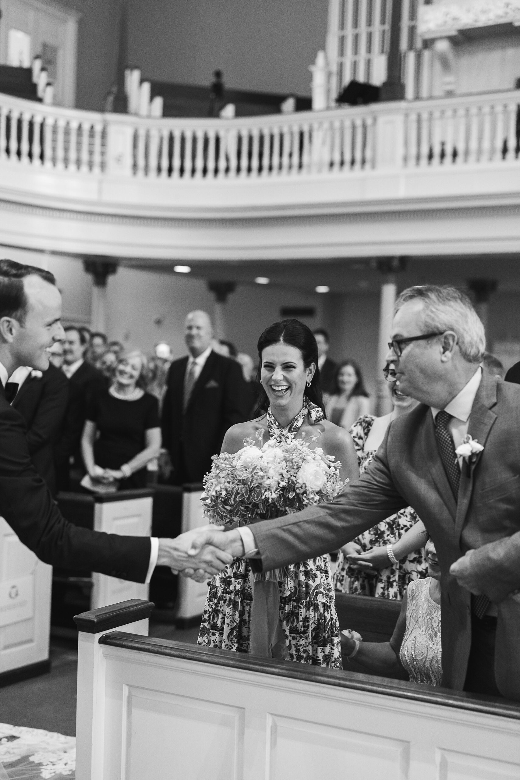 groom and father shake hands before ceremony in Old St. Joseph’s Catholic Church