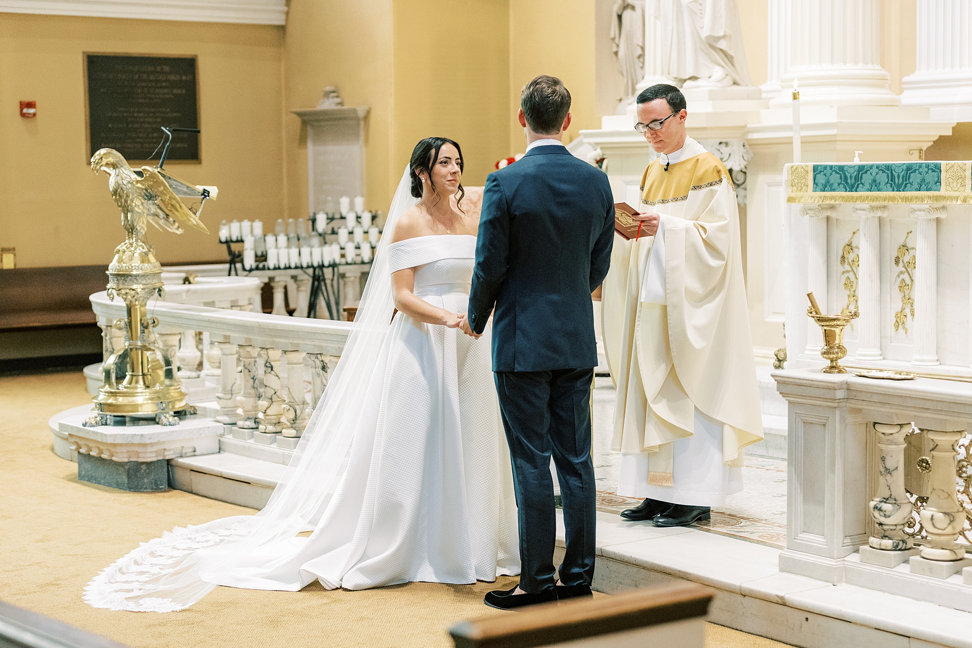 newlyweds listen to priest at Old St. Joseph’s Catholic Church in Philadelphia PA