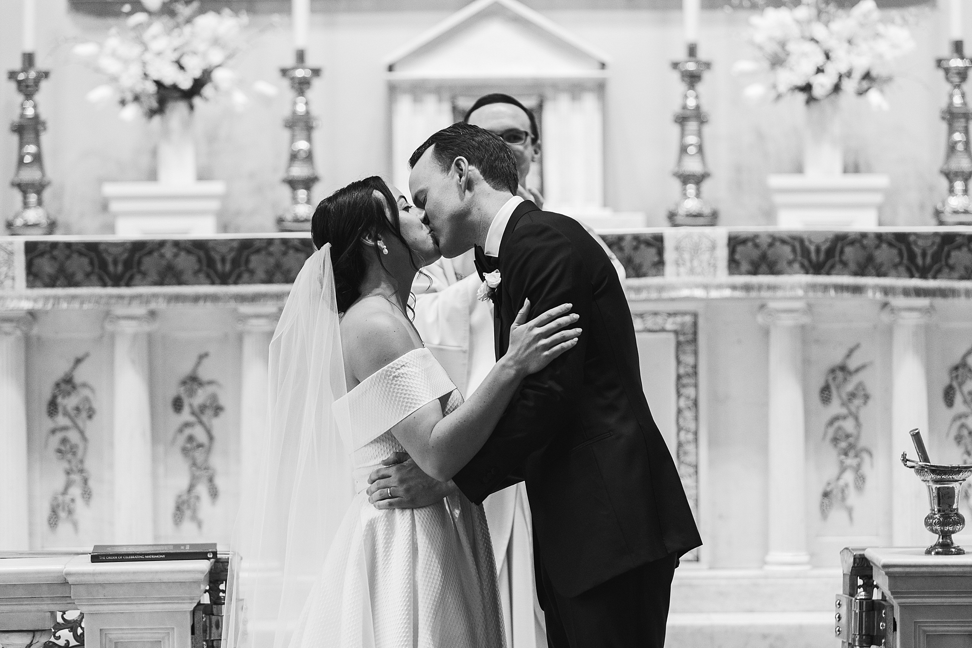 newlyweds kiss by alter inside Old St. Joseph’s Catholic Church in Philadelphia PA