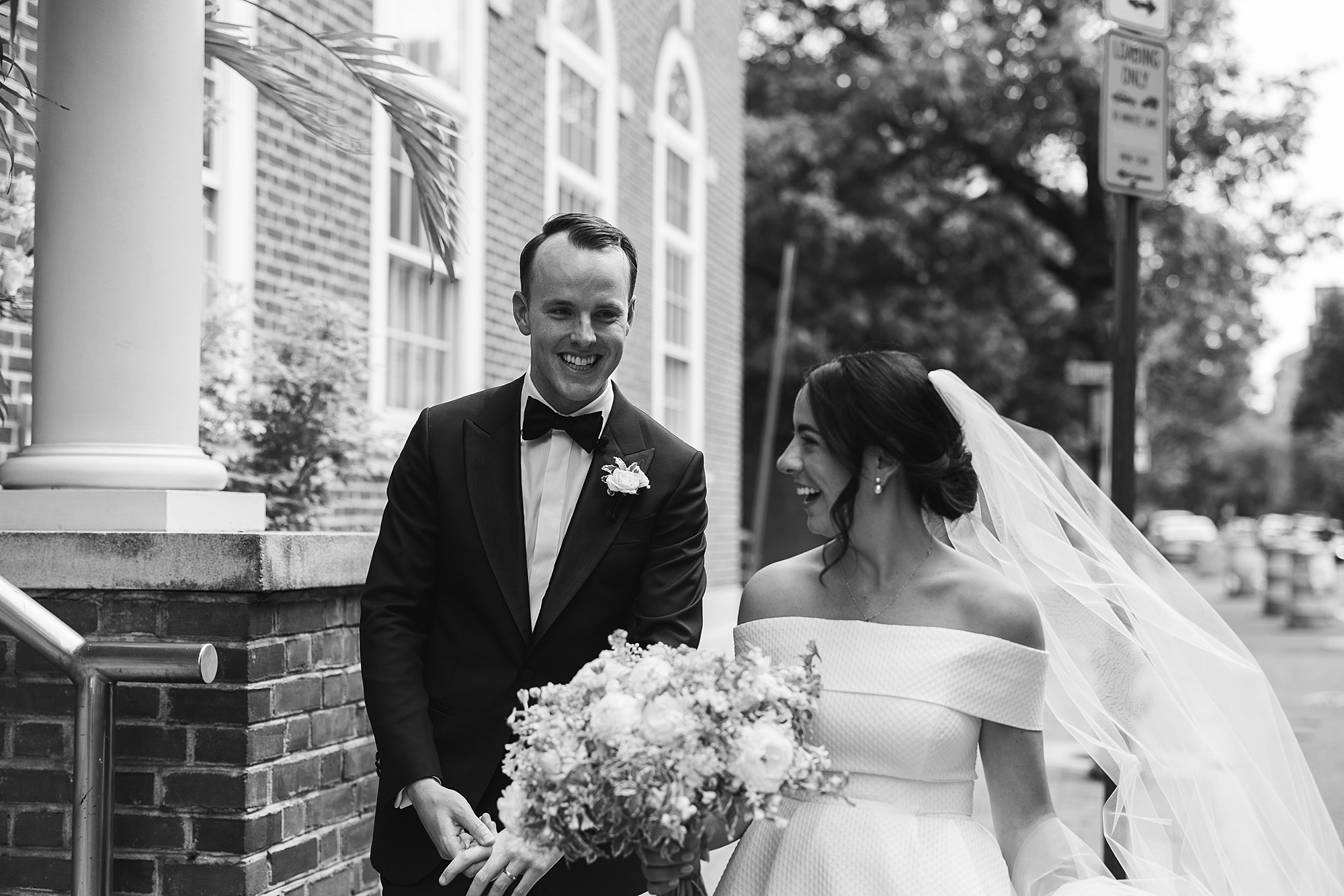 black and white portrait of a bride and groom giggling together on their wedding day