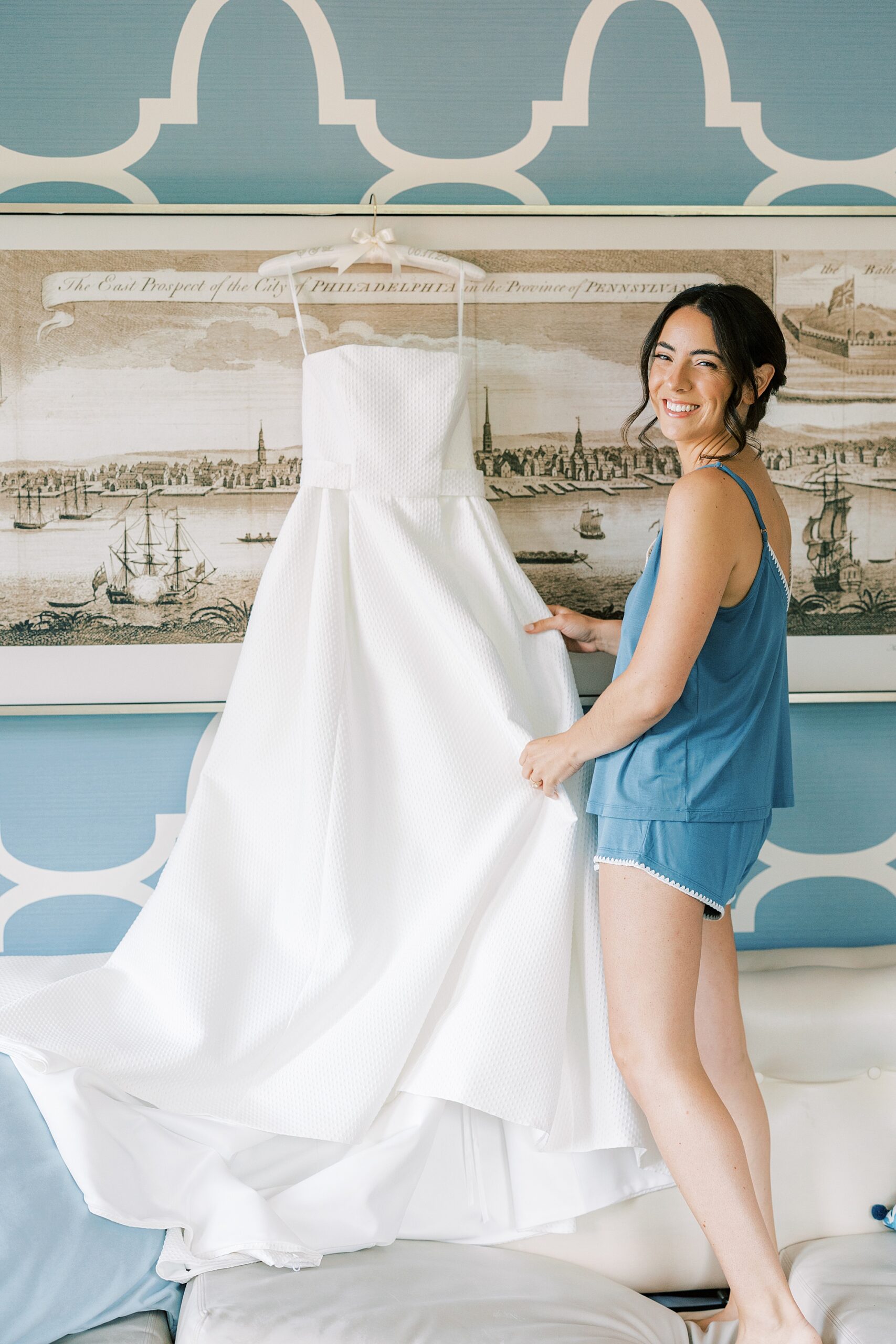 bride stands next to wedding gown hanging in the Hotel Monaco 