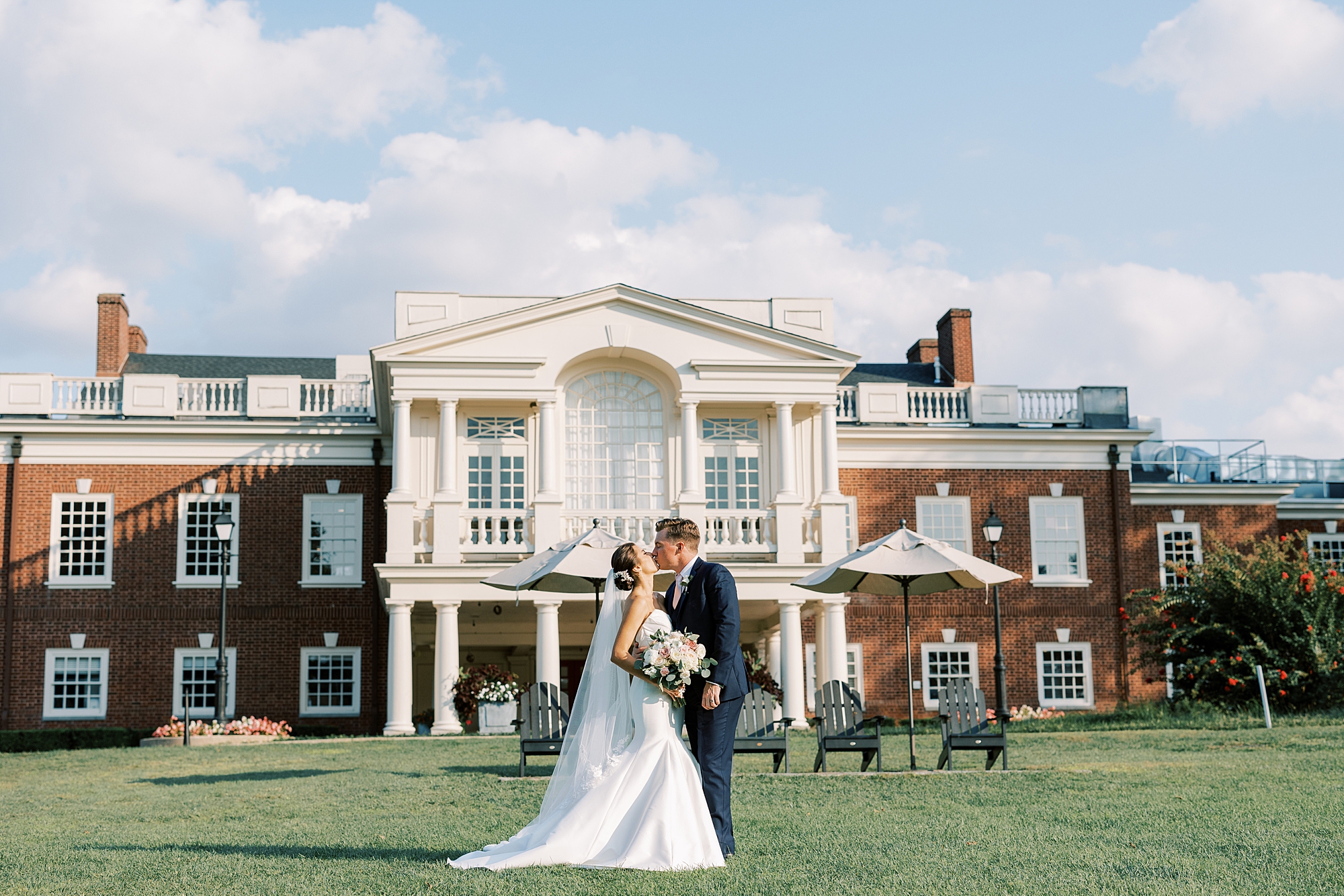 bride and groom kiss on lawn in front of the Philadelphia Cricket Club