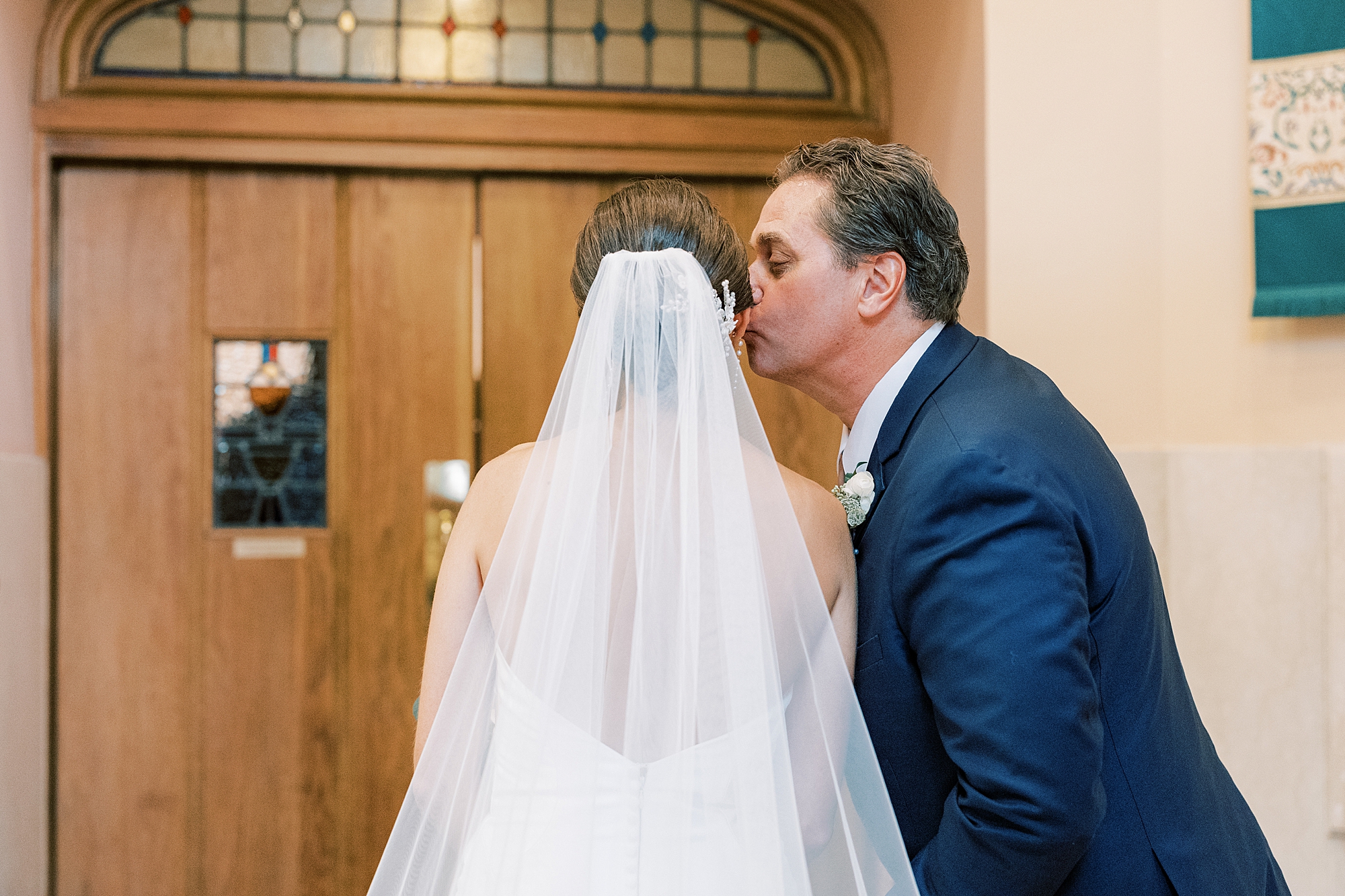 dad kisses bride's cheek before walking her down aisle for traditional wedding ceremony at Philadelphia PA church