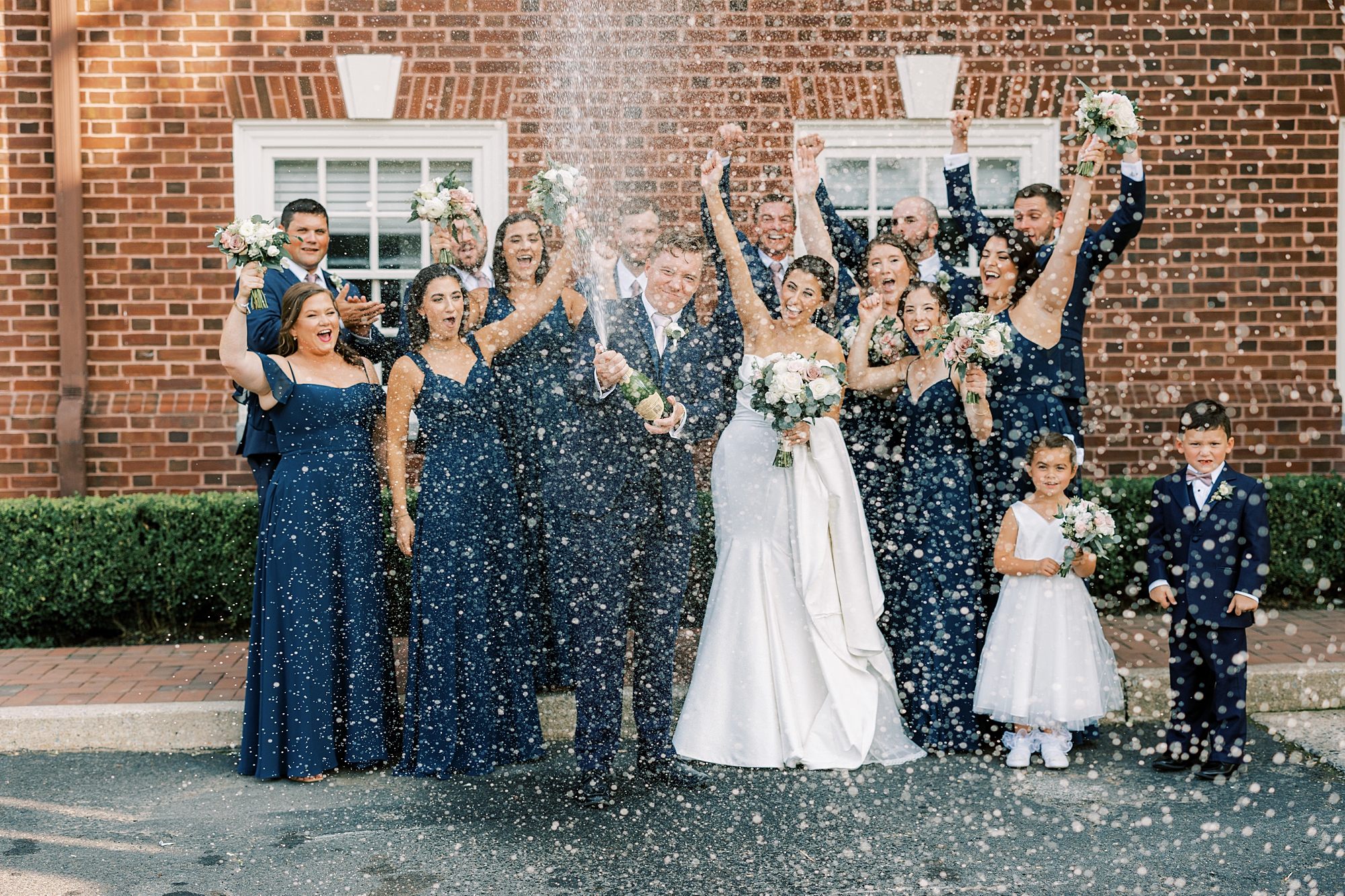 groom pops champagne in front of wedding party in Philadelphia PA