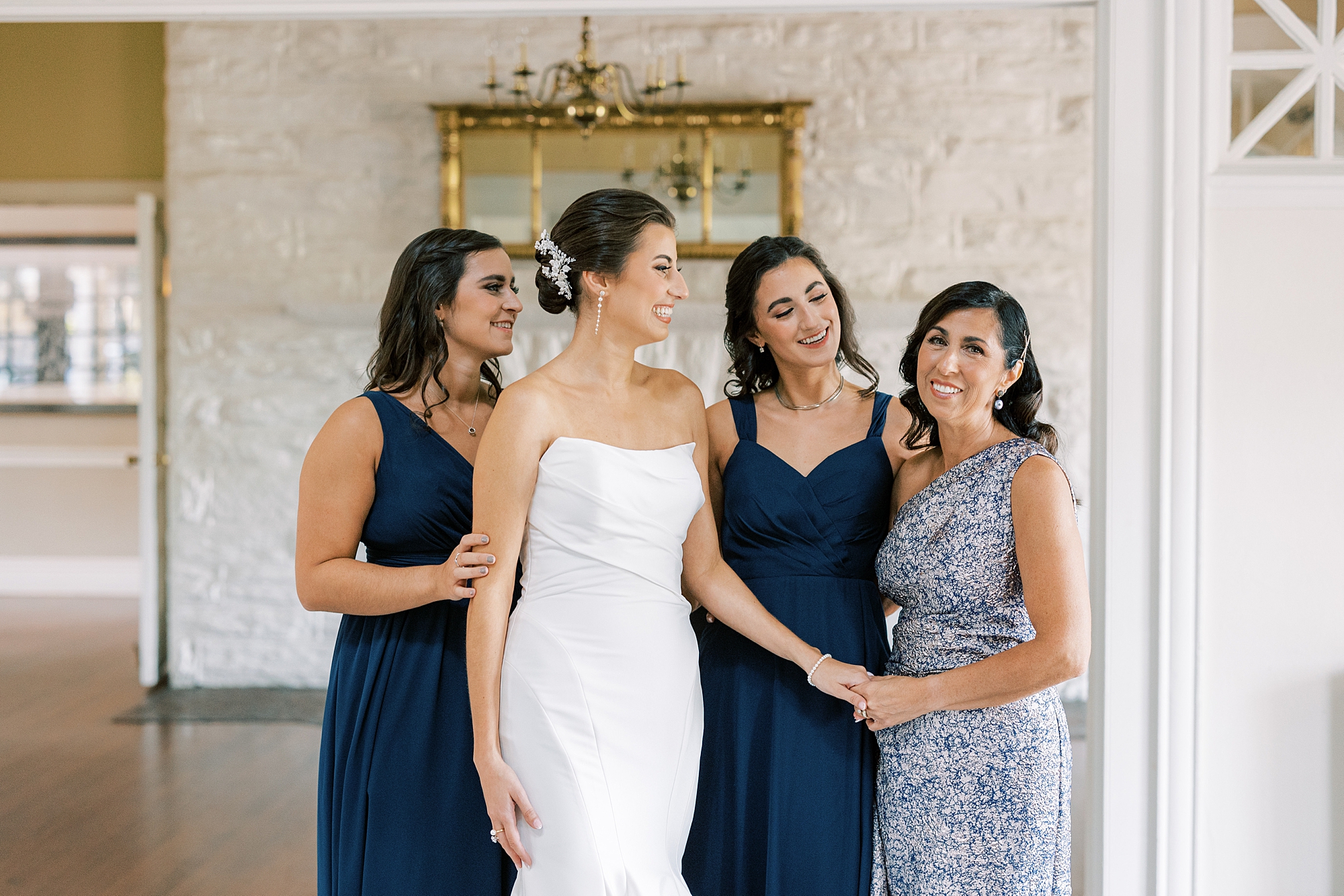 bride stands with bridesmaids in mismatched blue gowns 